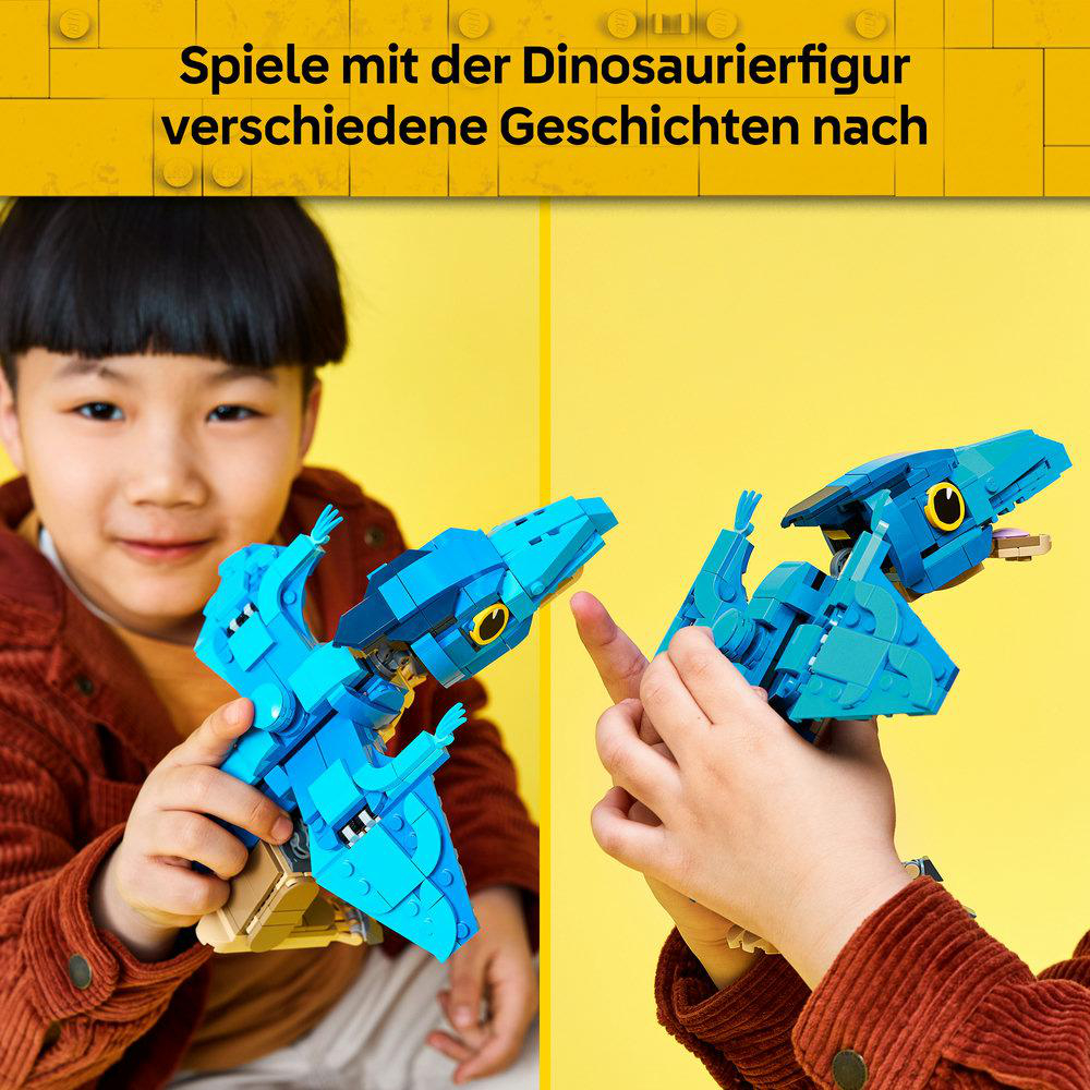 Ein Kind hält eine blaue LEGO-Dinosaurierfigur in den Händen, während es lächelt.