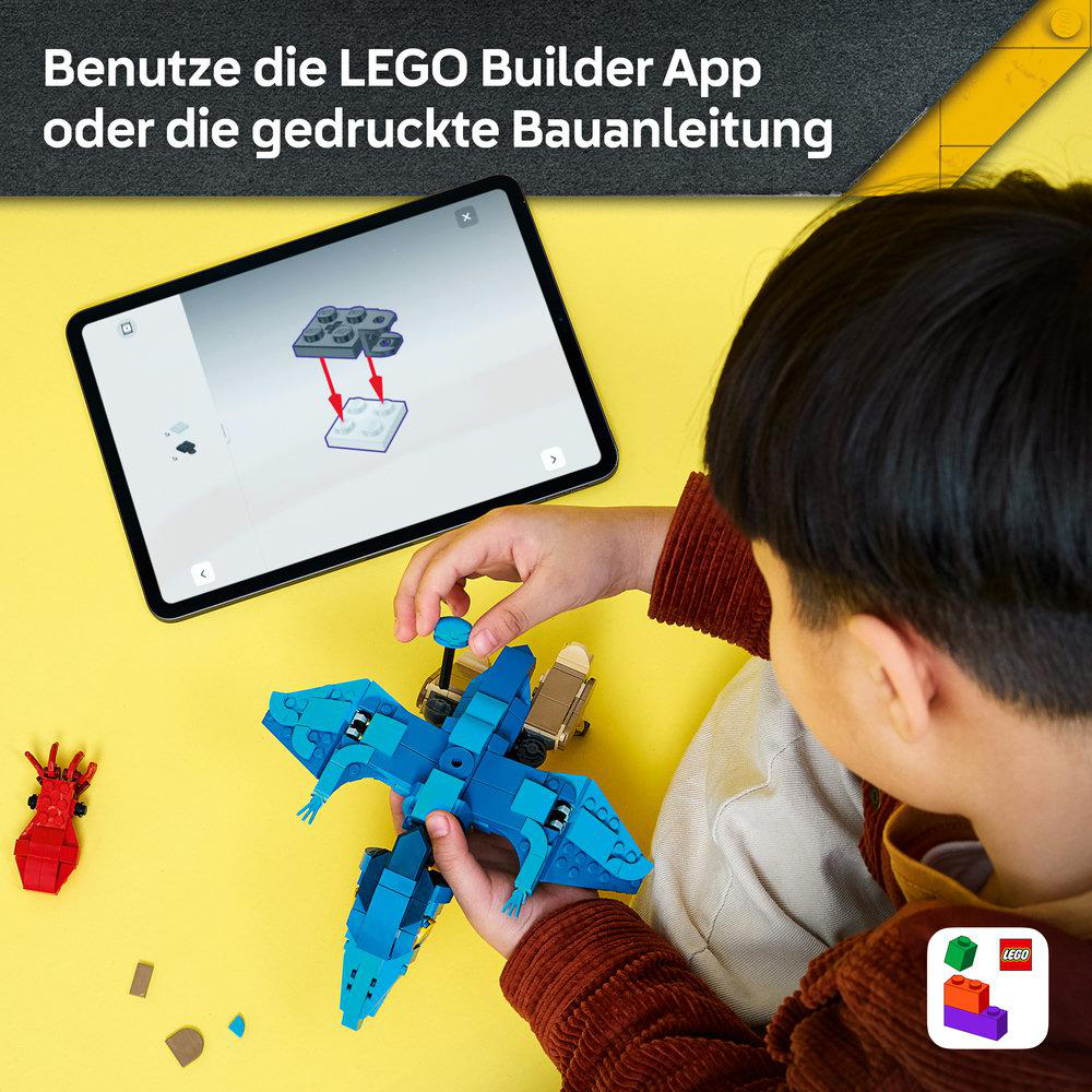 Kind baut eine blaue LEGO-Figur mit einer Tablet-App als Anleitung auf gelbem Tisch.