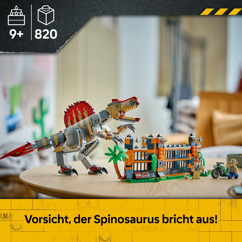 Lego Jurassic Park Set mit einem großen Spinosaurus, einem Gebäude, Minifiguren und einem Motorrad auf einem Tisch.