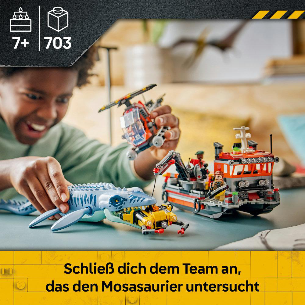 Ein Kind baut ein Lego-Set mit einem Mosasaurus, einem Hubschrauber, einem Boot und einer gelben Mini-U-Boot.