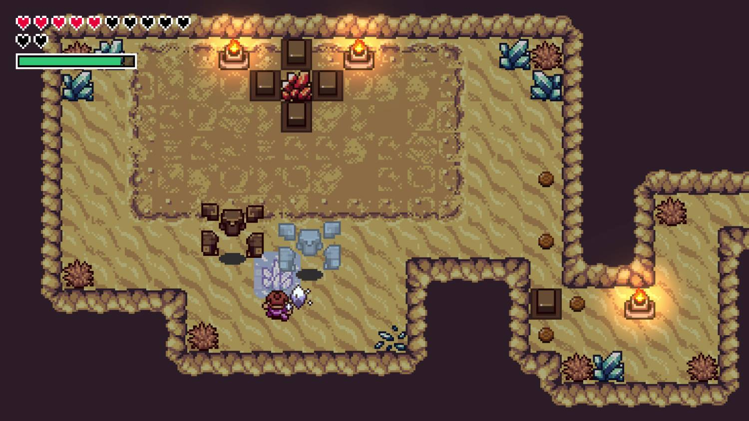 Un personaje está en una mazmorra de arena pixelada con cajas, cristales y luces.