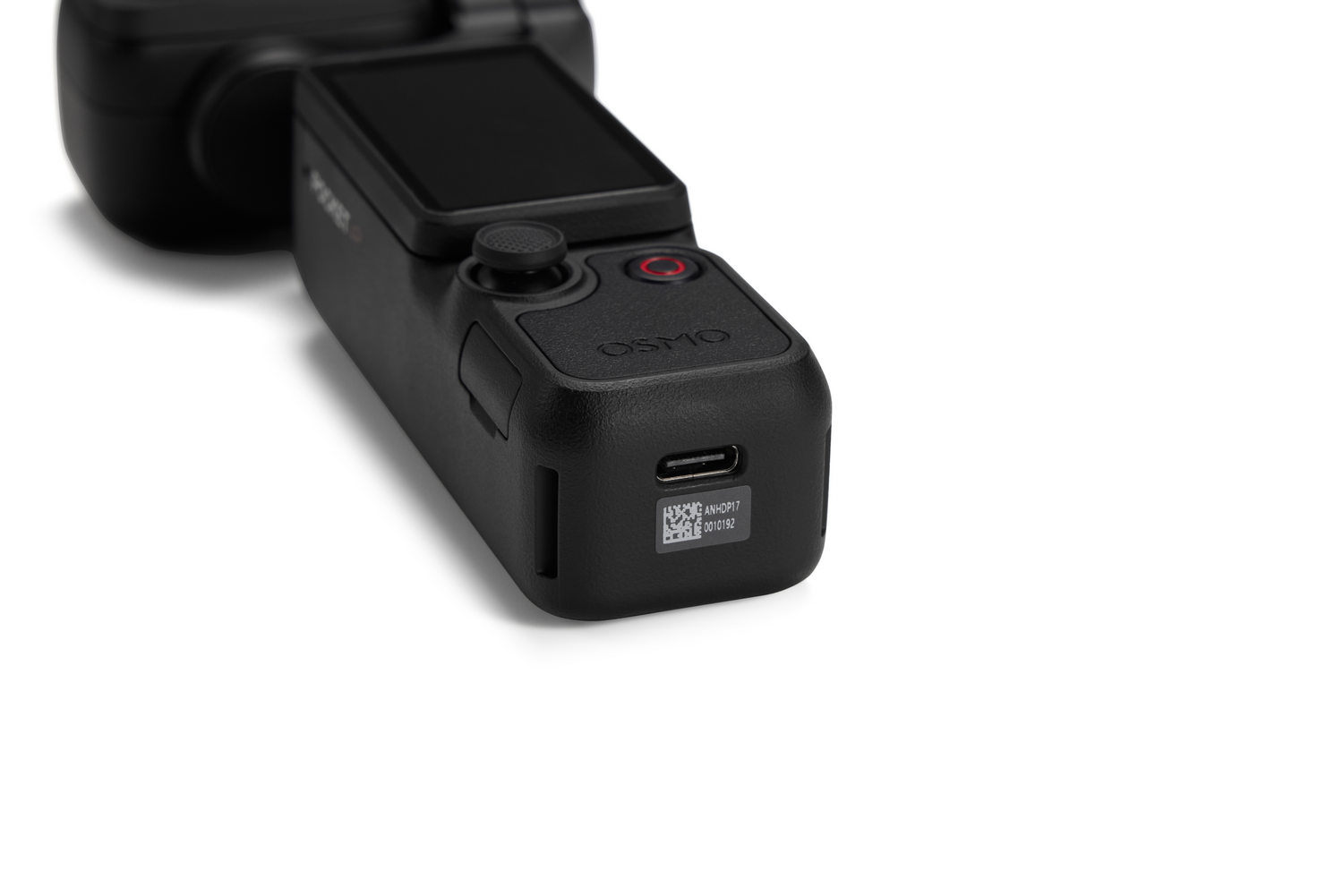 Primer plano de una cámara Osmo pocket negra sobre fondo blanco, destacando su puerto USB-C y etiqueta con código QR.