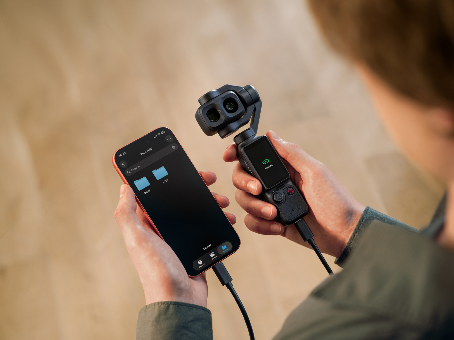 Una persona conecta un smartphone a una cámara Osmo Pocket 3 por cable.