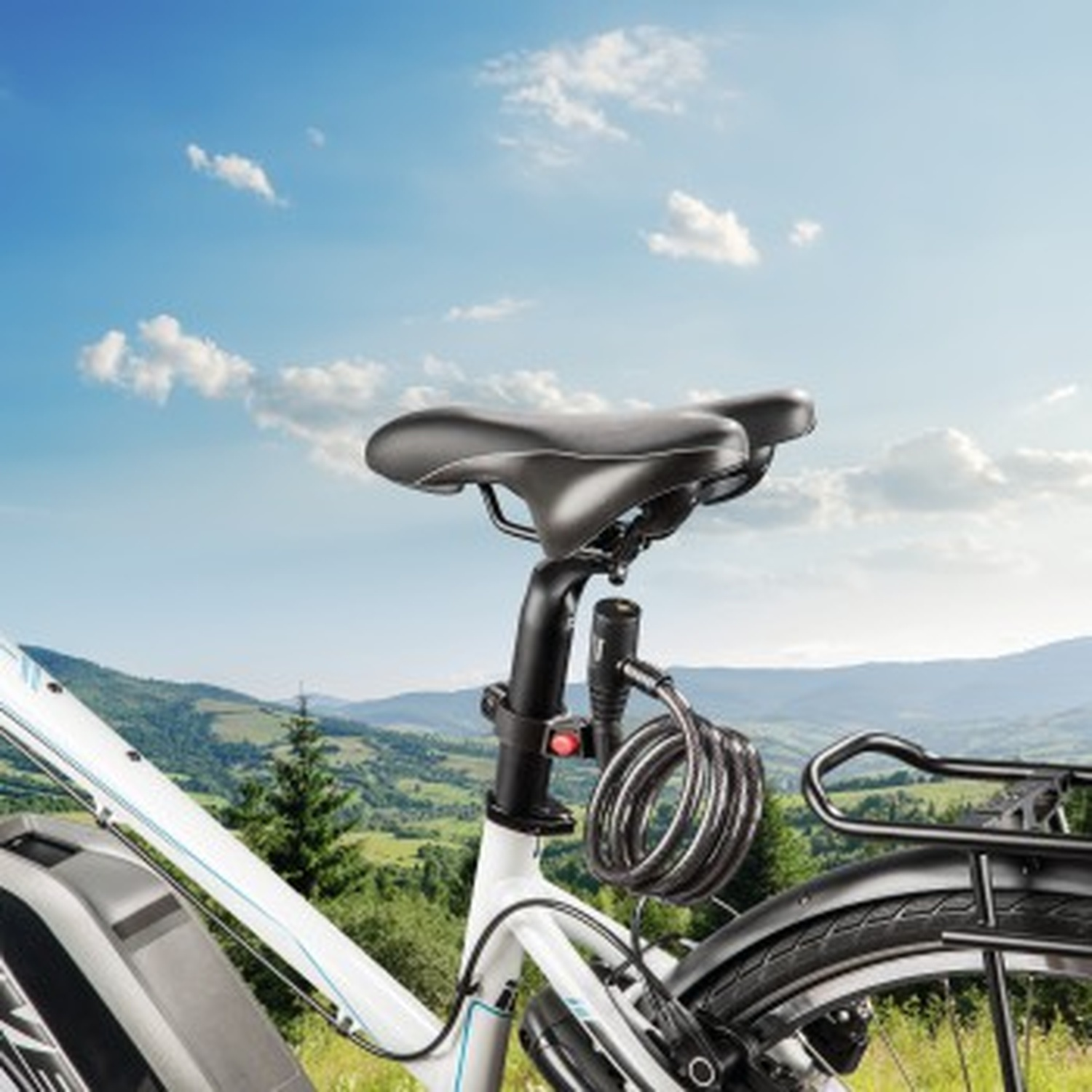 Une selle de vélo avec un antivol spirale fixé à la tige de selle, sur fond de collines vertes et de ciel bleu.