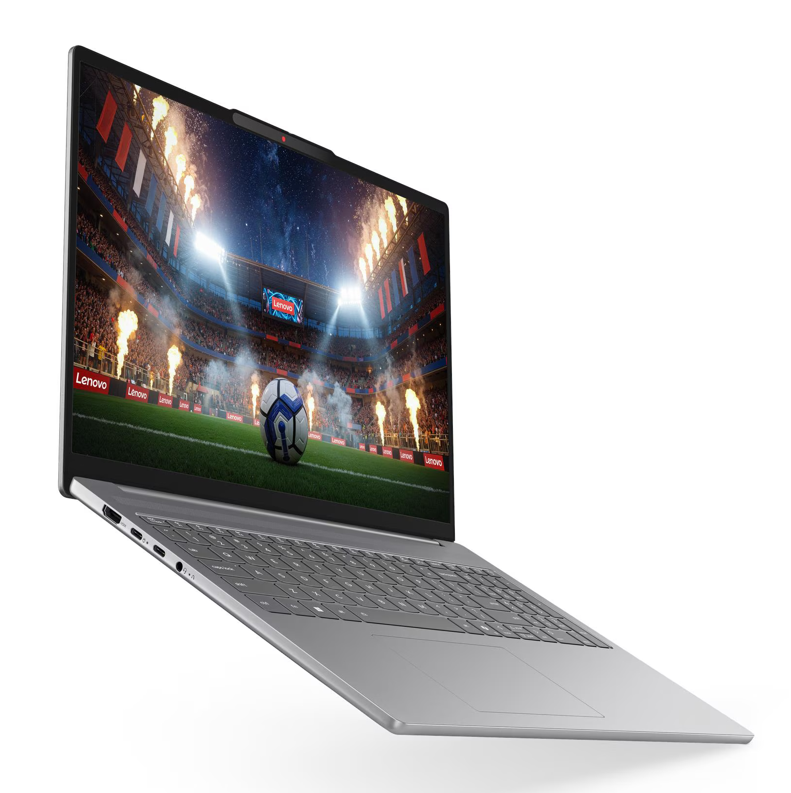 Srebrny laptop na białym tle wyświetla stadion piłkarski z fajerwerkami na ekranie.