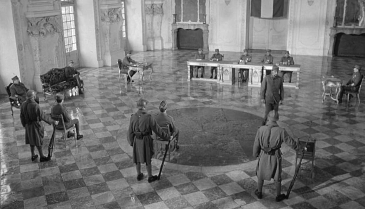 Historisches Schwarzweißfoto einer Militärgerichtsverhandlung in einem großen Saal mit Schachbrettboden.