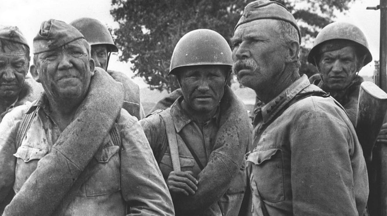 Schwarz-Weiß-Foto von sowjetischen Soldaten in Uniform mit Helmen und Ausrüstung outdoors.