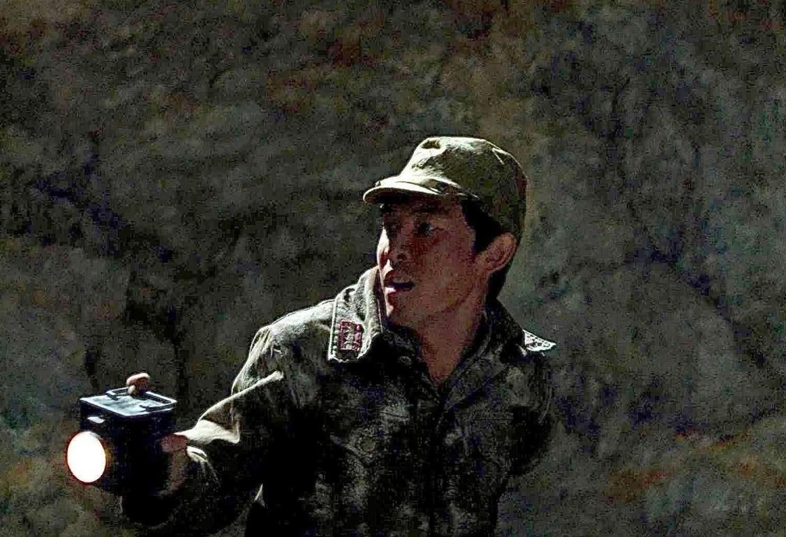 Ein Mann im Militäruniform hält in einer dunklen Höhle eine leuchtende Taschenlampe.