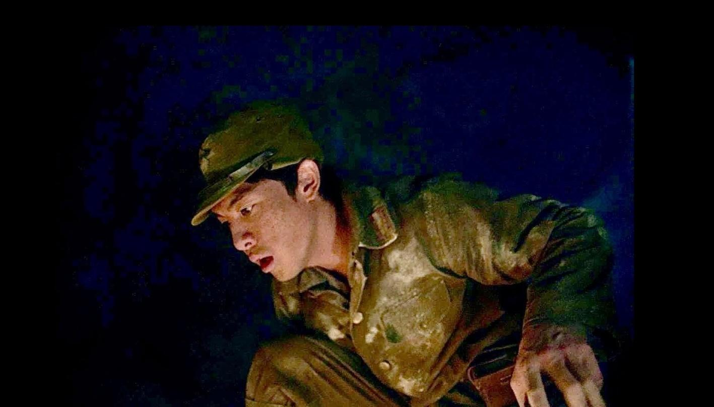 Ein Soldat in schmutziger Uniform kauert im Dunkeln.