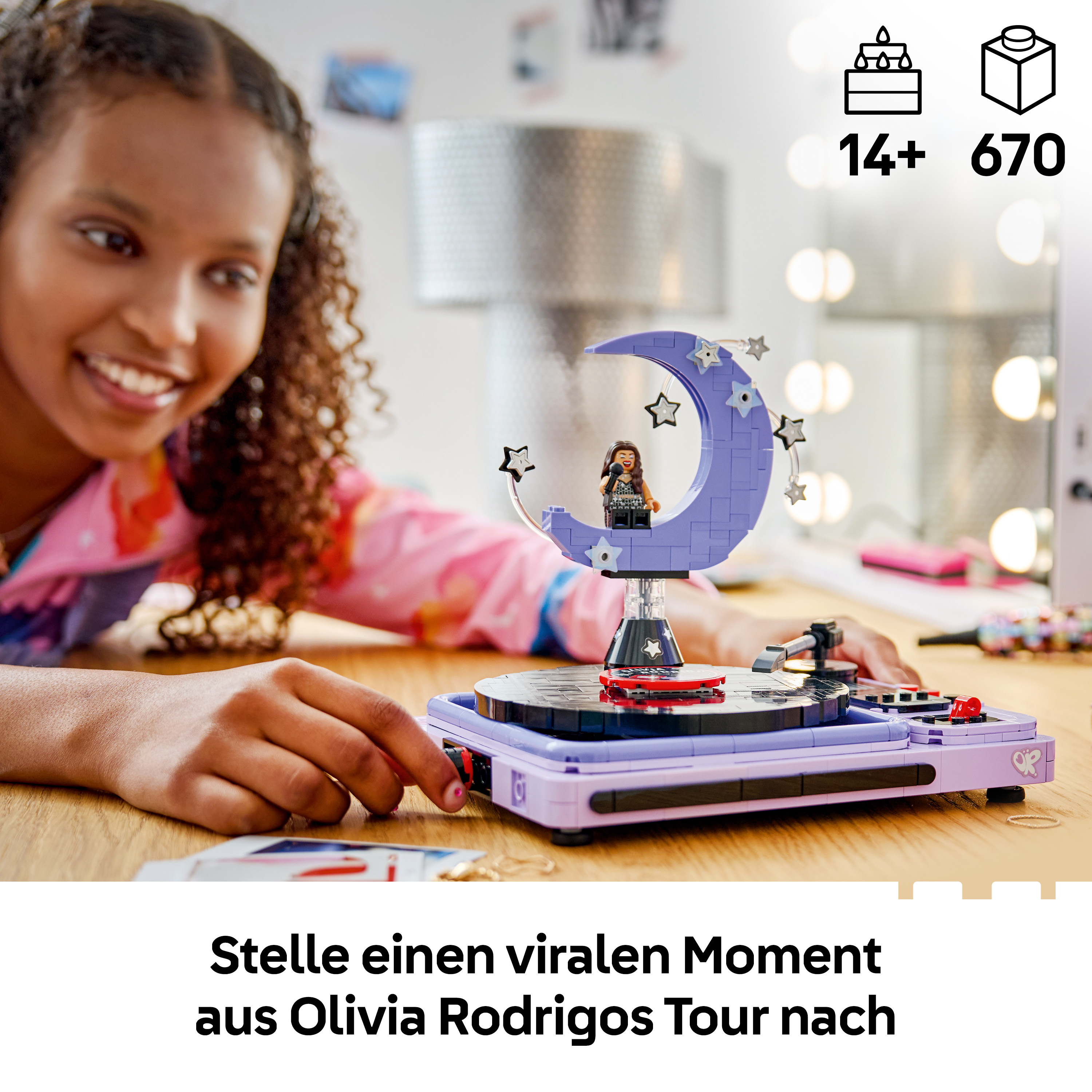 Ein lächelndes Mädchen spielt mit einem violetten Lego-Musikbühnenset mit drehendem Mond und Minifigur.