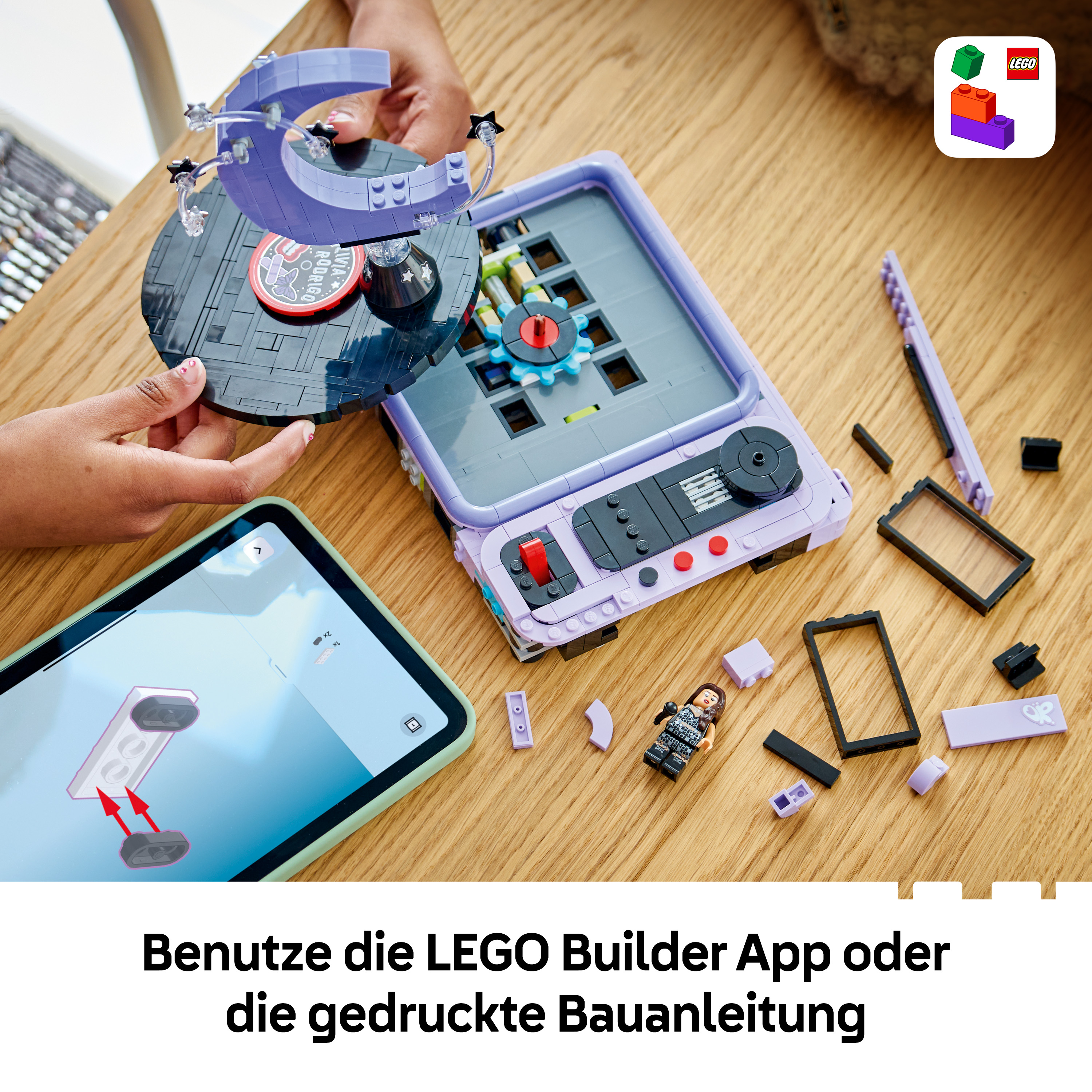 Ein Kind baut ein violettes Lego-Set auf einem Holztisch mit einer Bauanleitung auf einem Tablet.