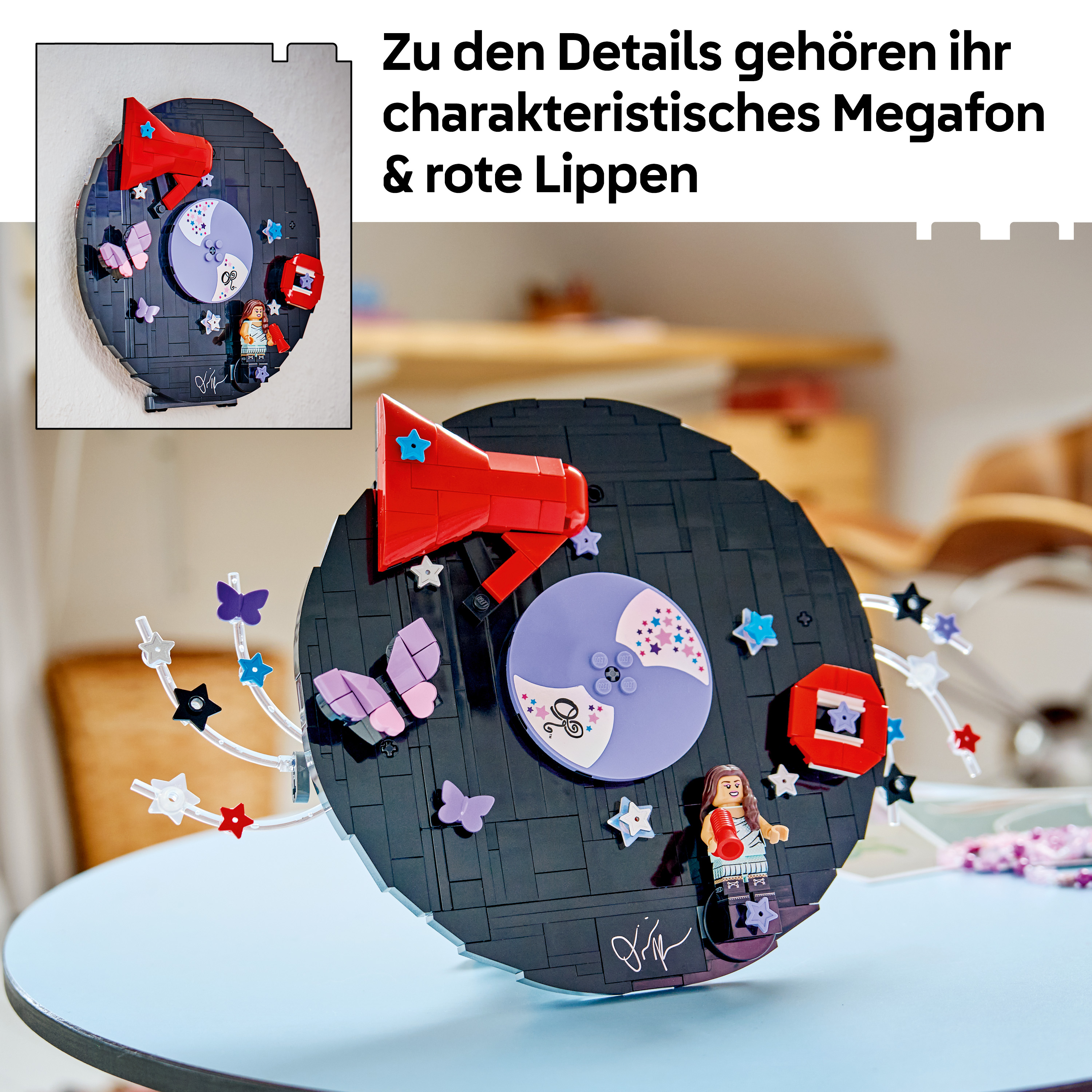 Lego-Schallplatten-Kunstwerk auf blauem Tisch mit rotem Megafon, Schmetterlingen, Sternen und Minifigur.