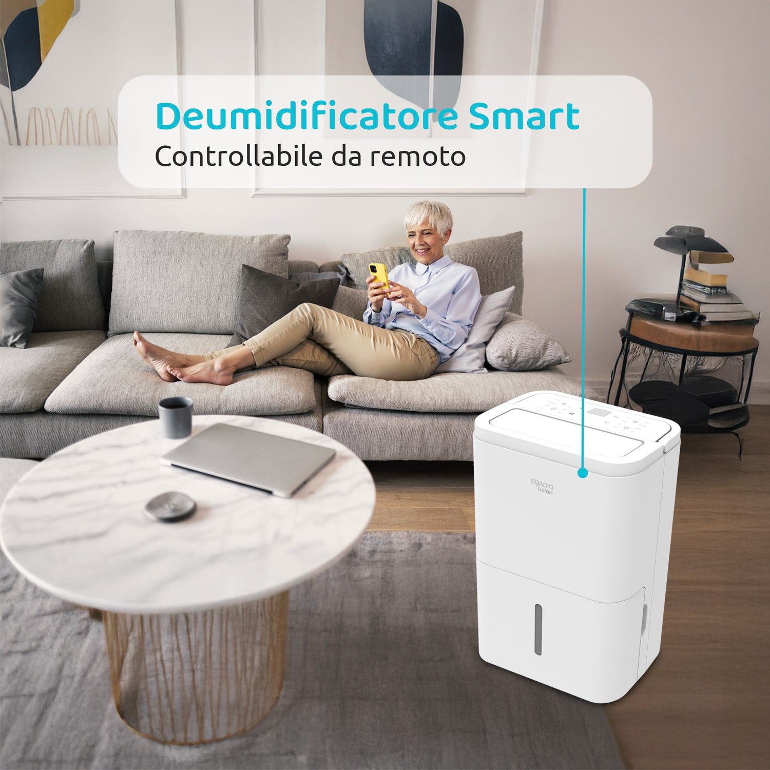 Anziana sul divano con smartphone giallo; accanto un deumidificatore smart bianco.