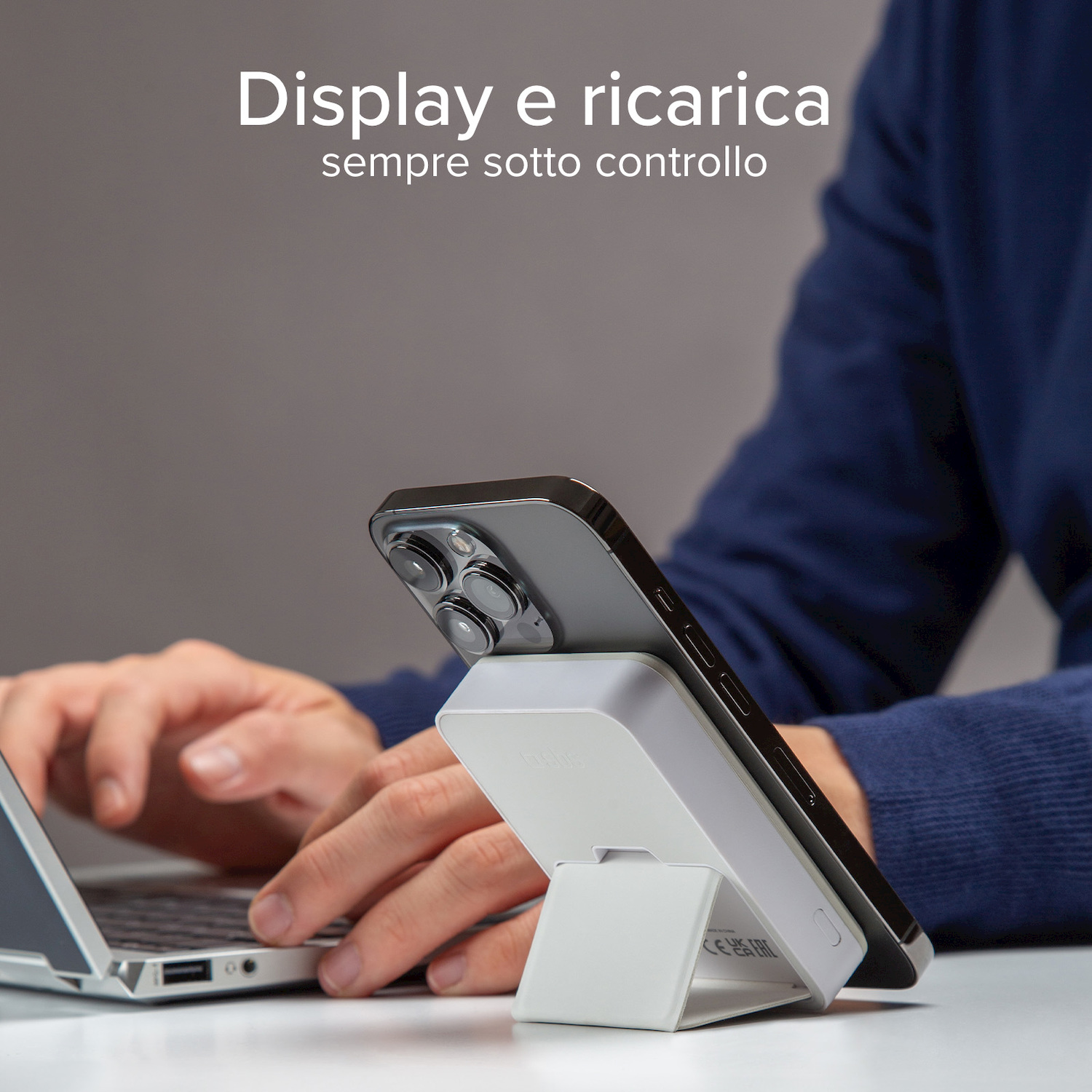 Smartphone in carica su supporto bianco mentre si digita.