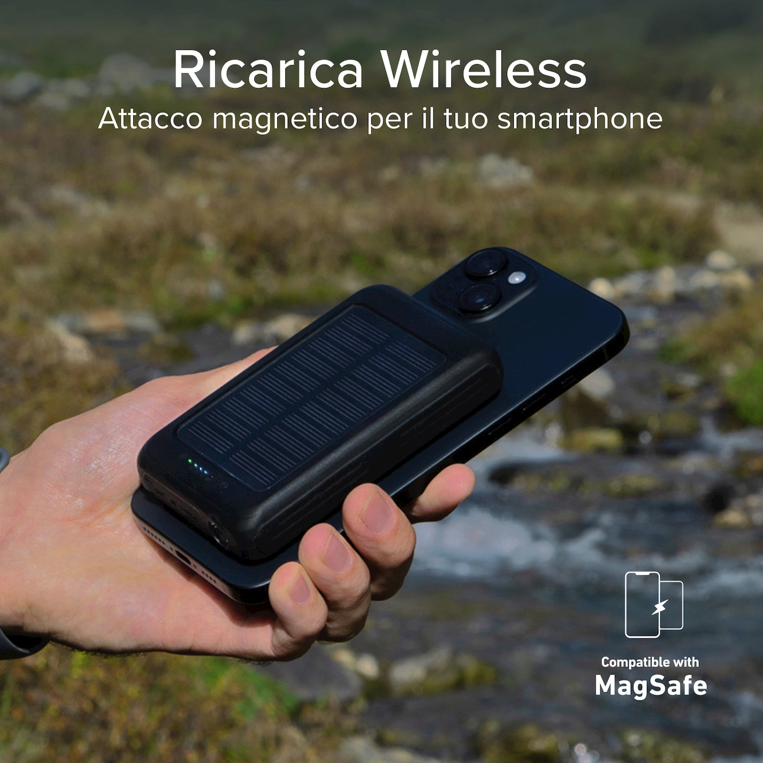 Una mano sostiene uno smartphone nero con caricatore solare magnetico, all'aperto.