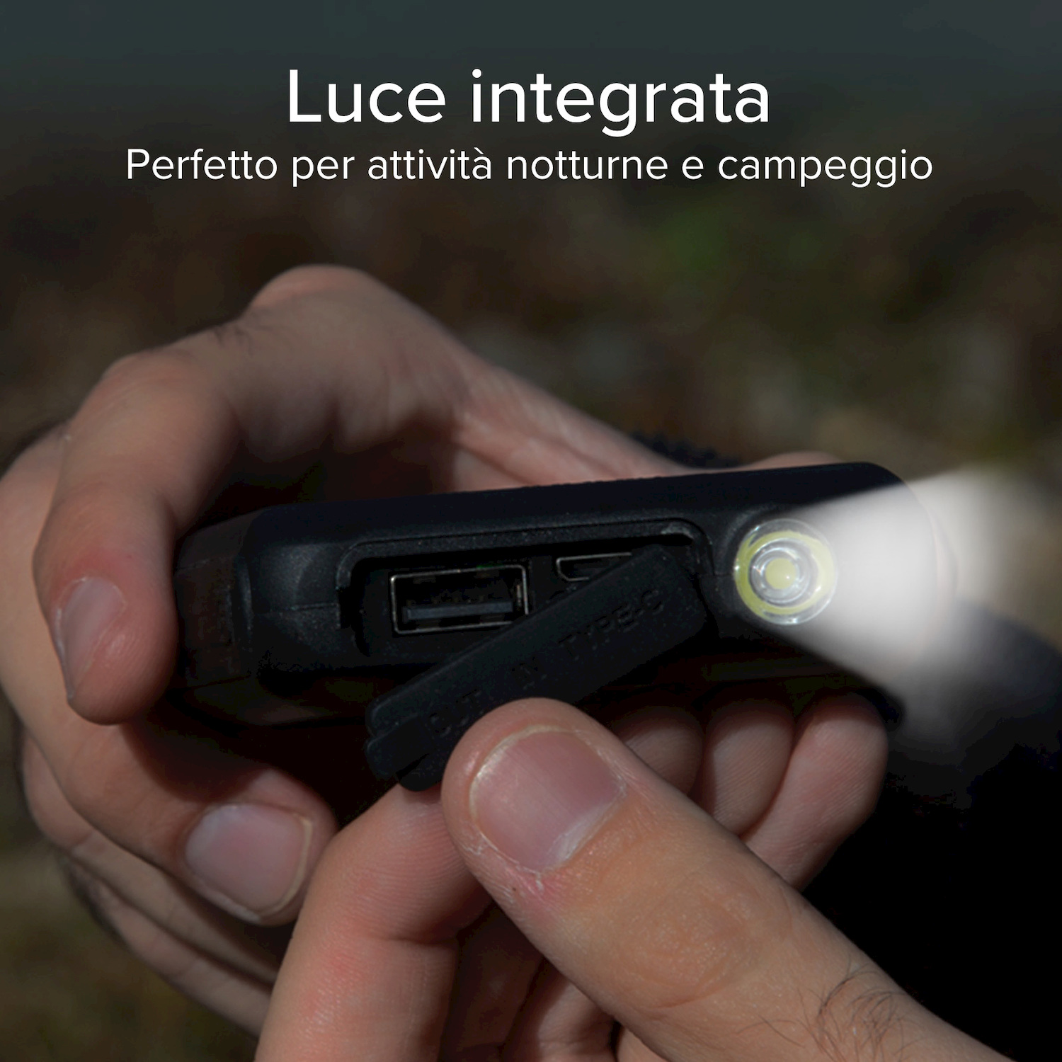 Una mano apre il coperchio delle porte di un power bank con torcia LED integrata.