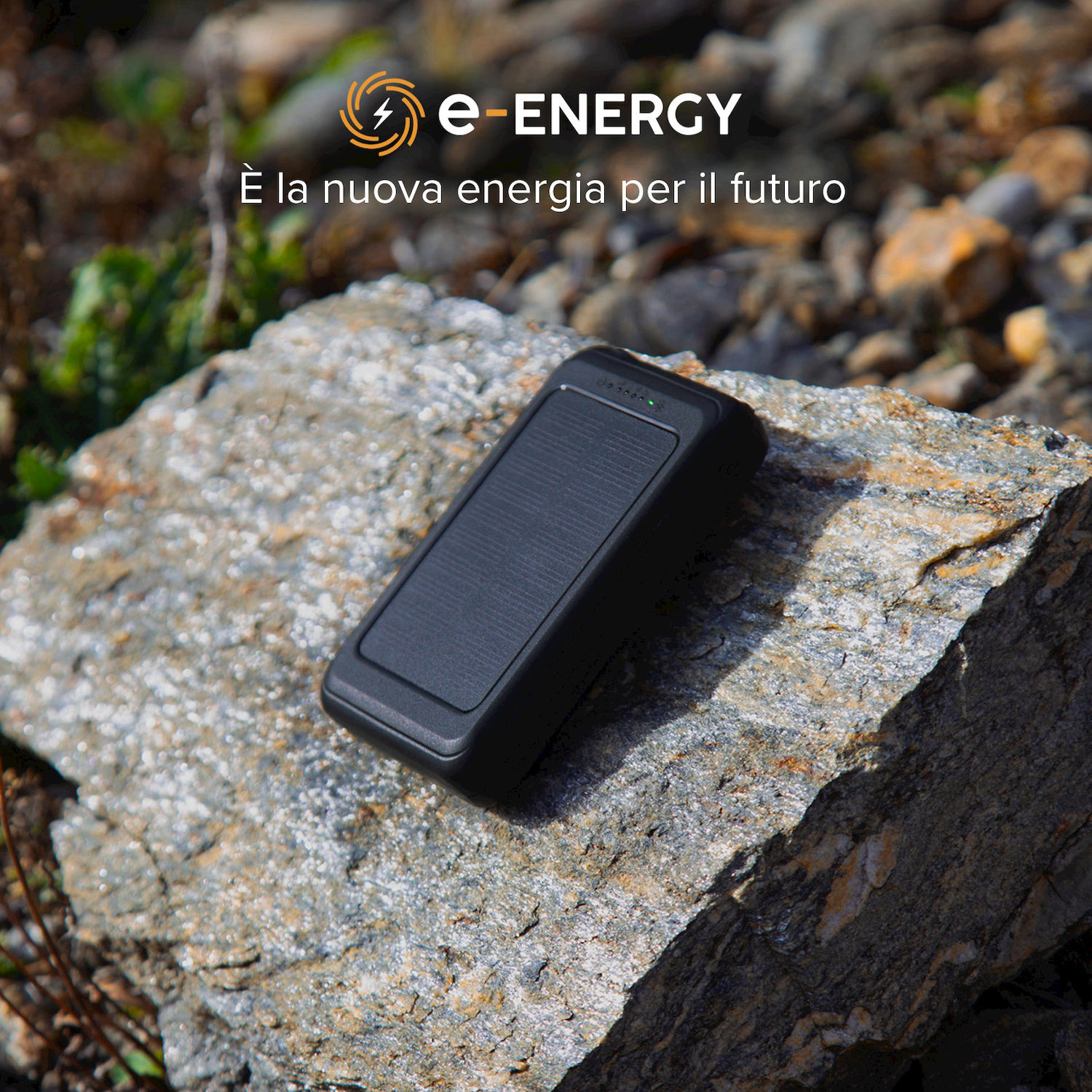 Un power bank nero poggia su una grande pietra grigia all'aperto.