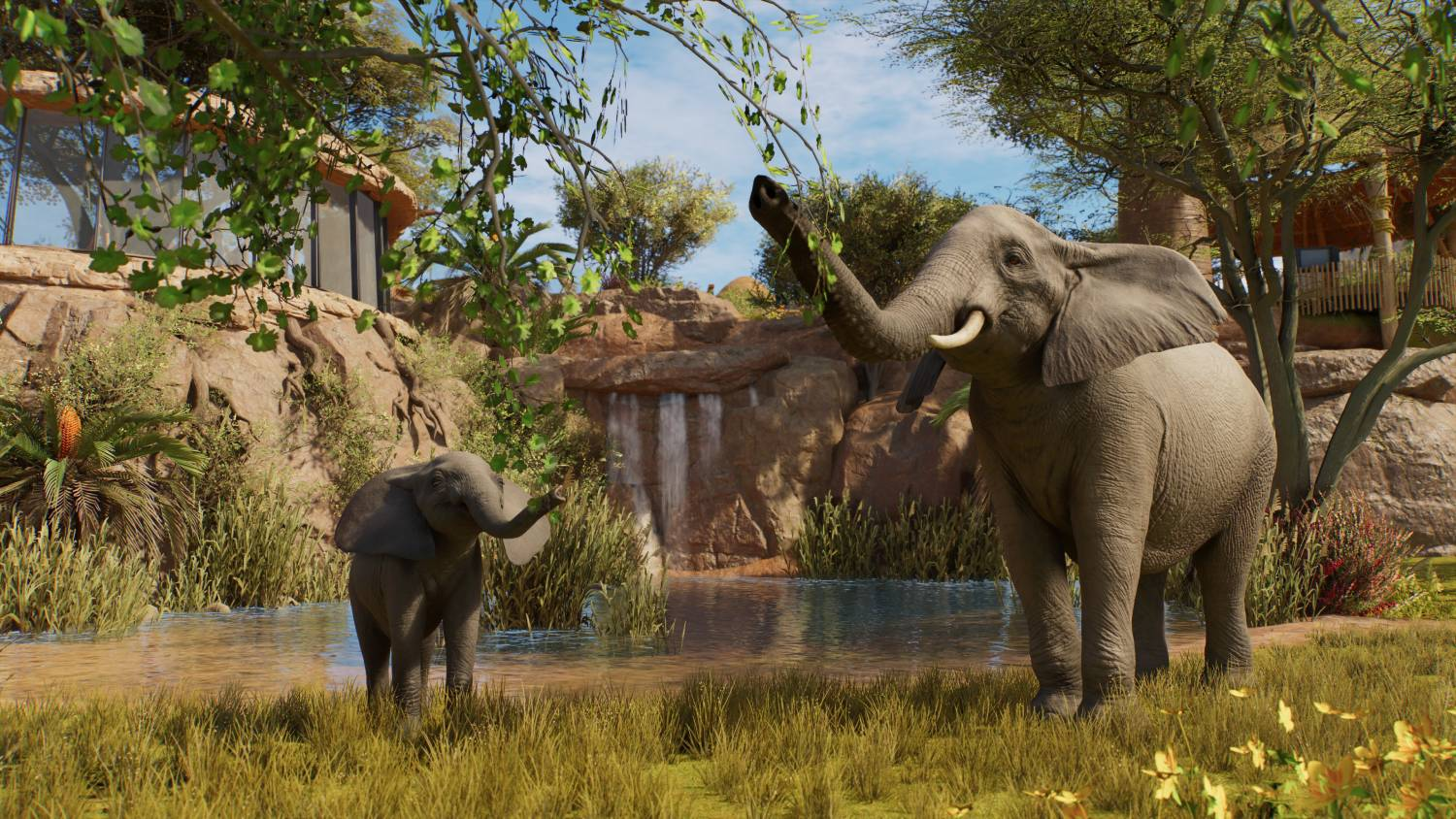 Un elefante adulto y una cría están en un paisaje verde junto a un río con acantilados rocosos.