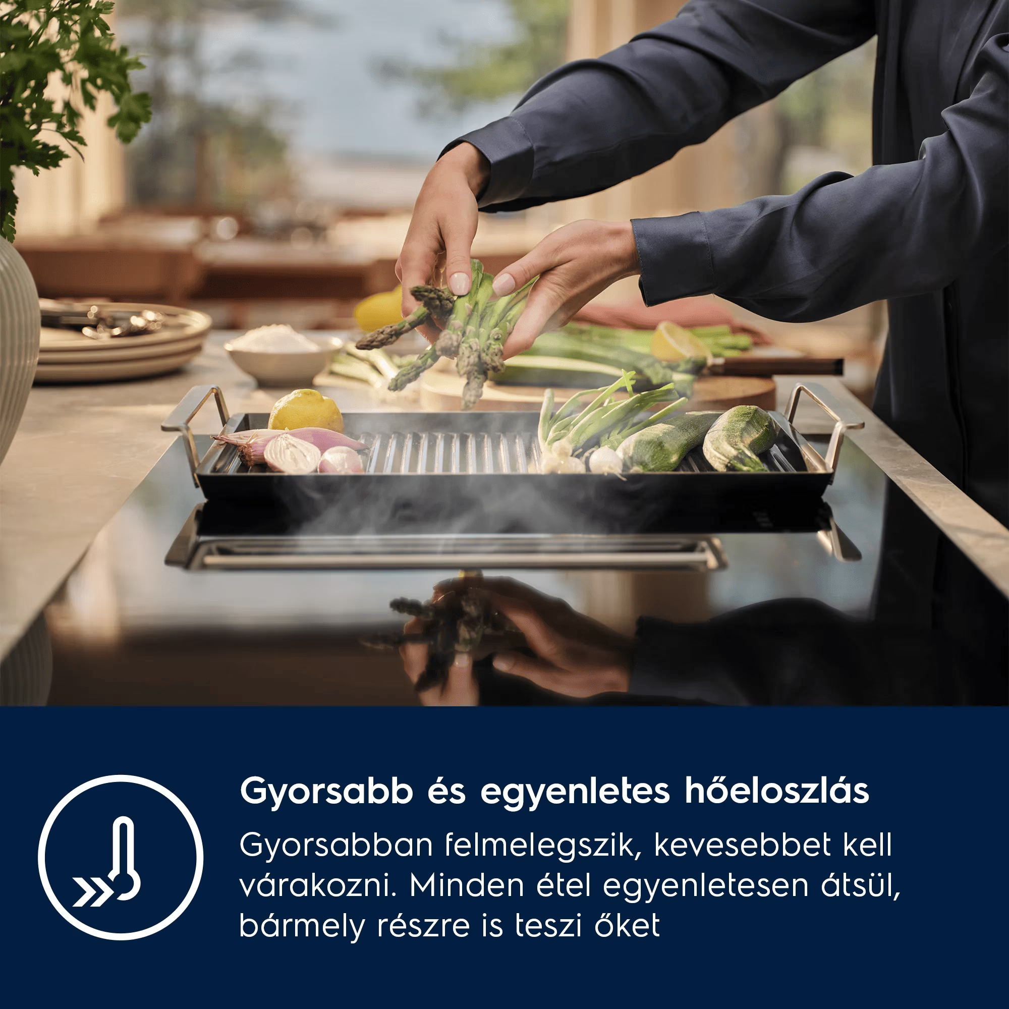 Egy személy spárgát helyez egy grillserpenyőbe egy beépített elszívós főzőlapon.