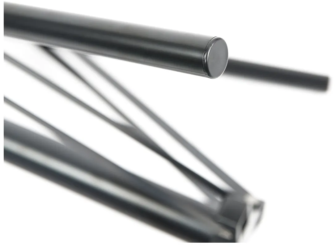 Gros plan de tubes métalliques noirs avec un capuchon de protection sur fond blanc.