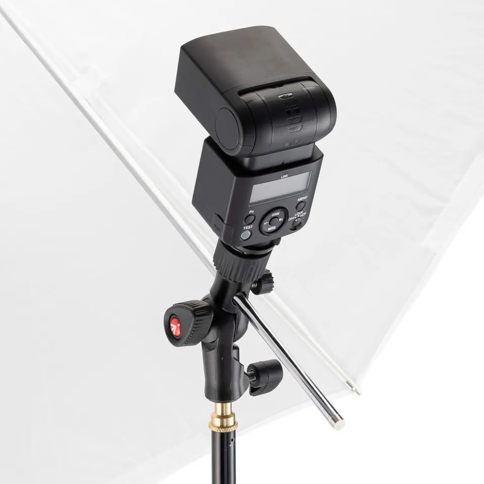 Un flash per fotocamera nero montato su un supporto davanti a un ombrello bianco.
