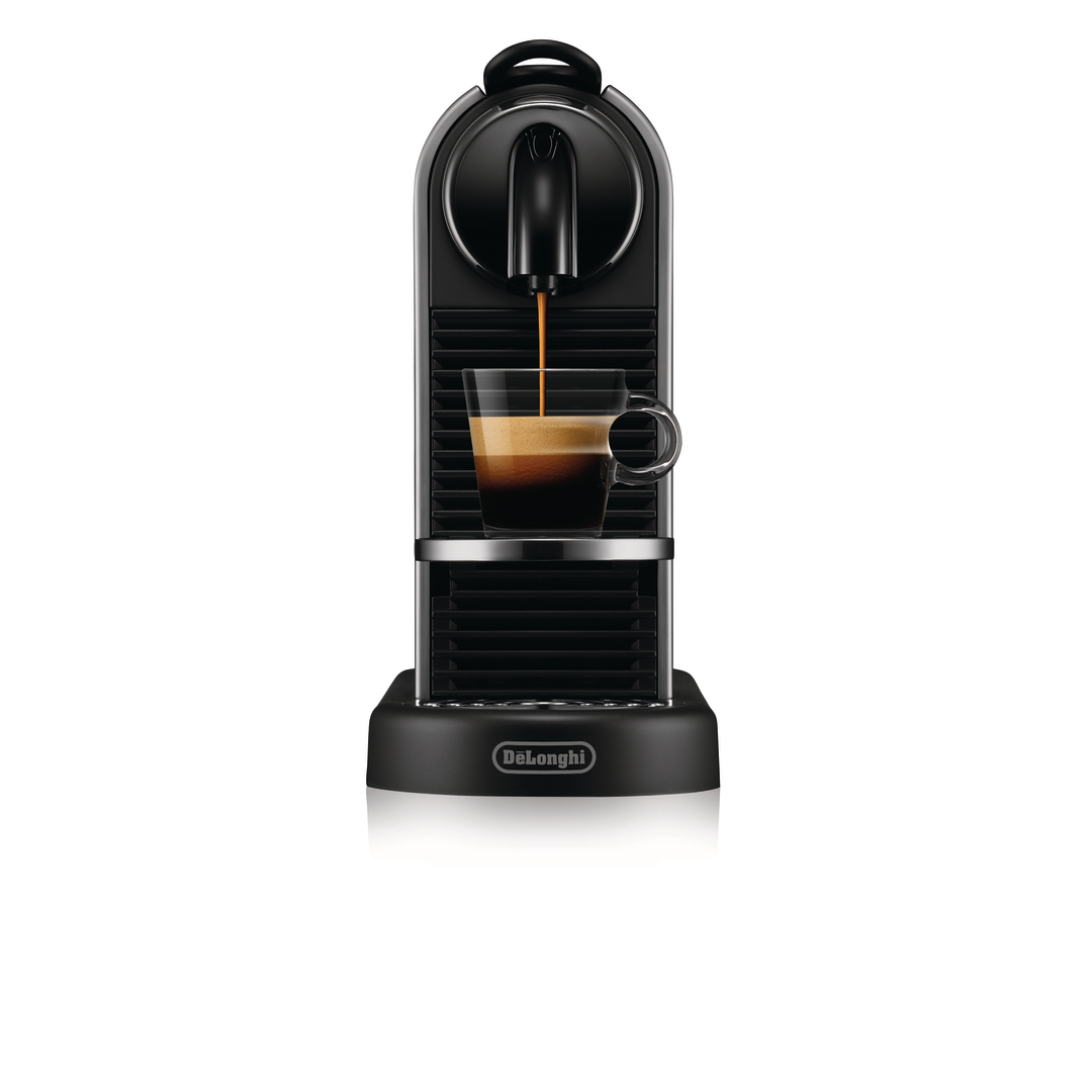 Schwarze DeLonghi Kaffeemaschine füllt eine transparente Glastasse mit Espresso auf weißem Hintergrund.