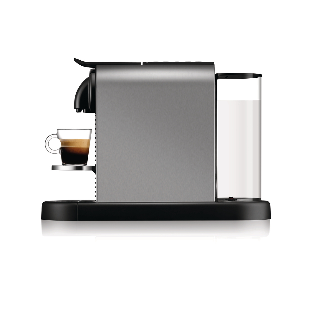 Moderne silberne Kaffeemaschine mit Wassertank und gefüllter Glastasse auf weißem Hintergrund.