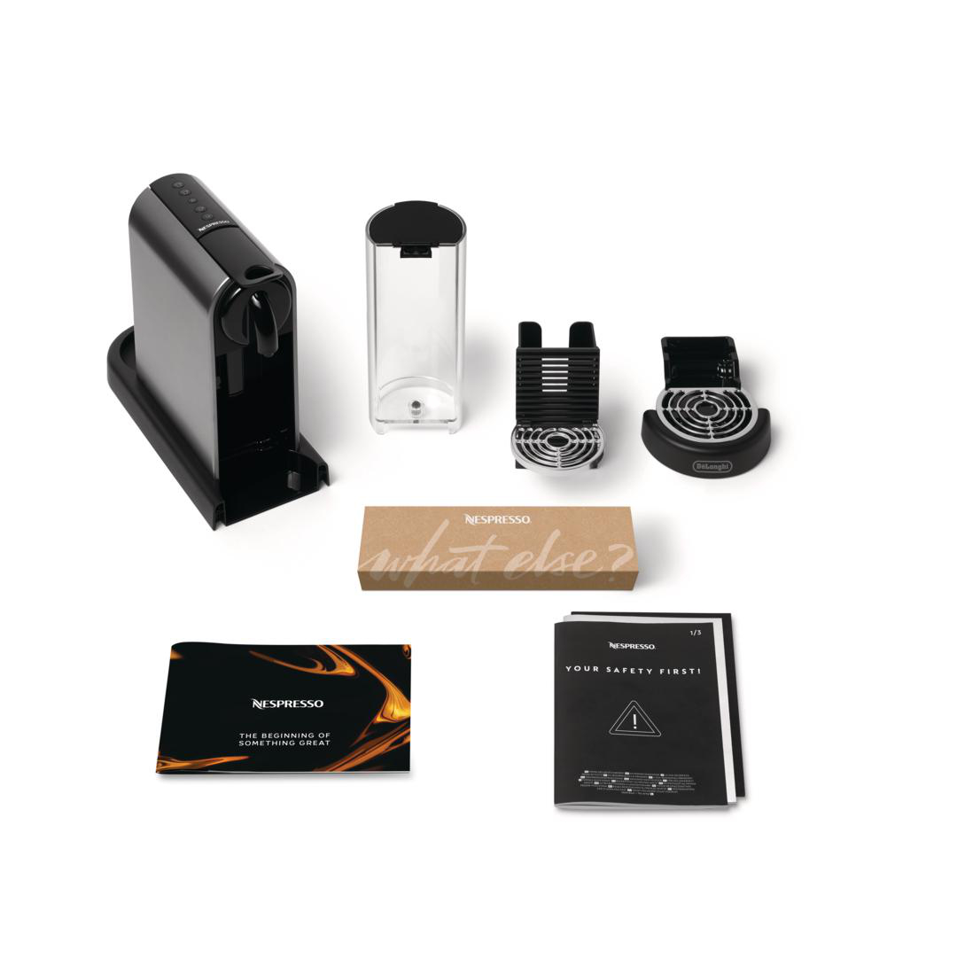 Eine schwarze Nespresso-Kaffeemaschine mit abnehmbarem Wassertank, Tropfschalen, Kapselbox und Bedienungsanleitungen.