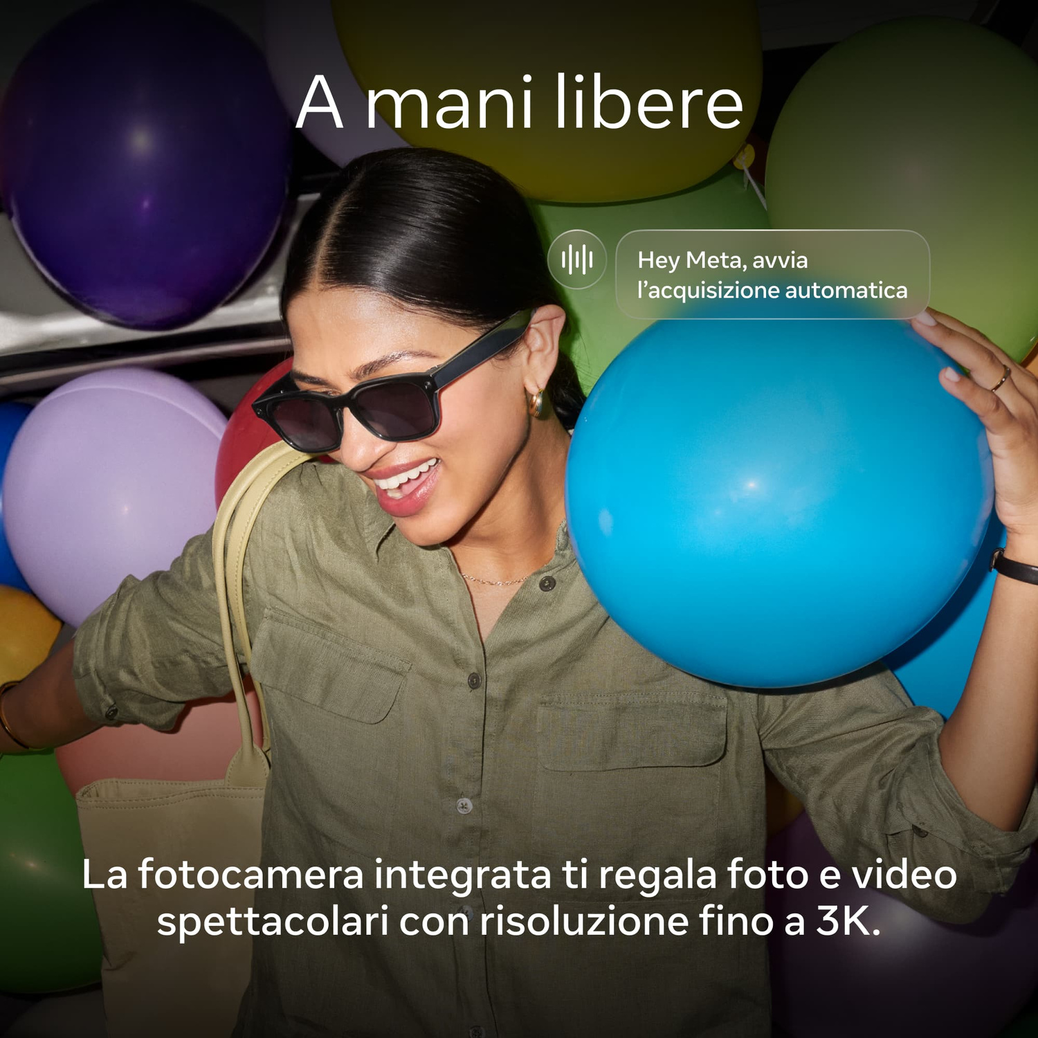 Una donna sorridente con occhiali da sole e camicia verde posa circondata da palloncini colorati.