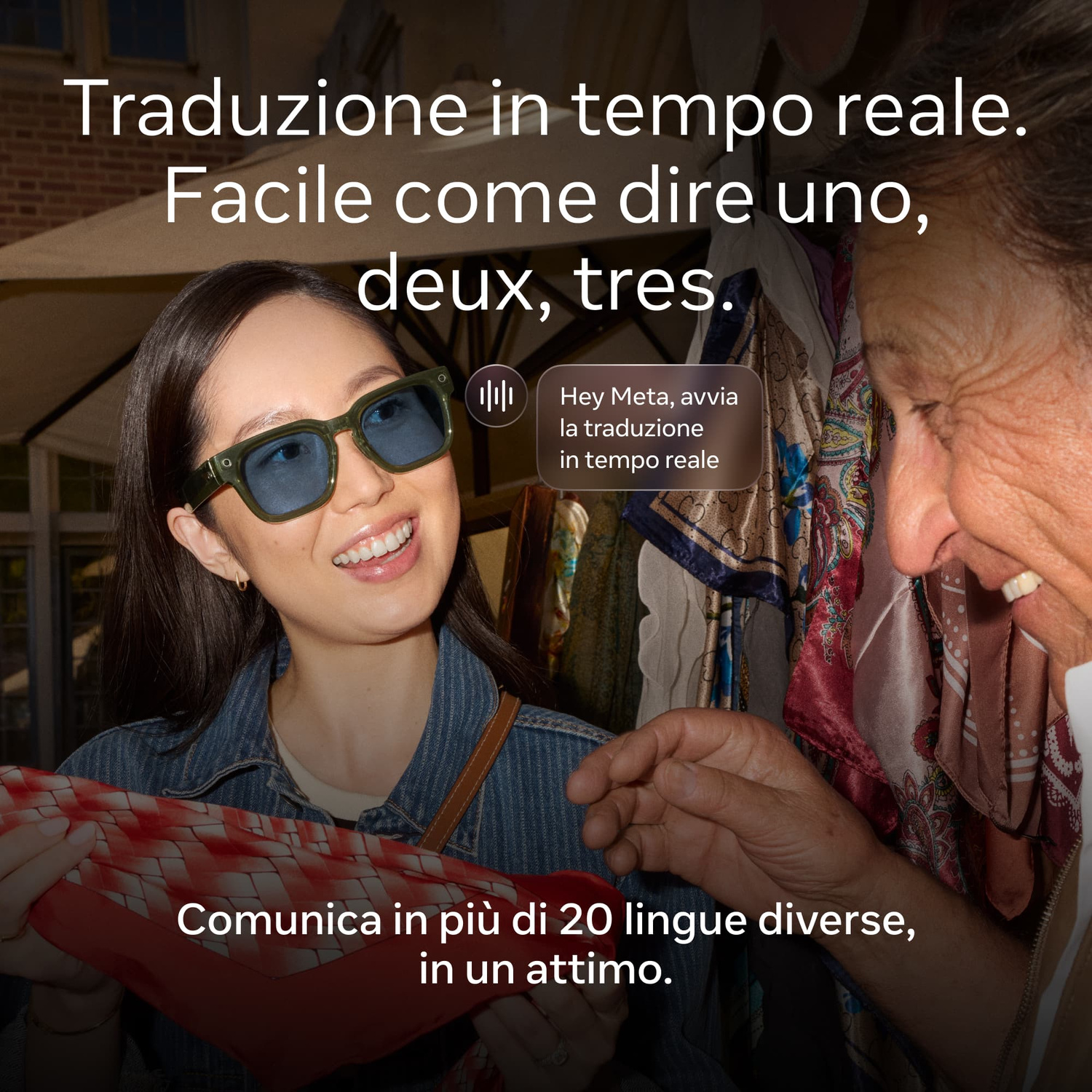 Una donna con occhiali da sole blu e un uomo parlano all'aperto guardando dei tessuti.