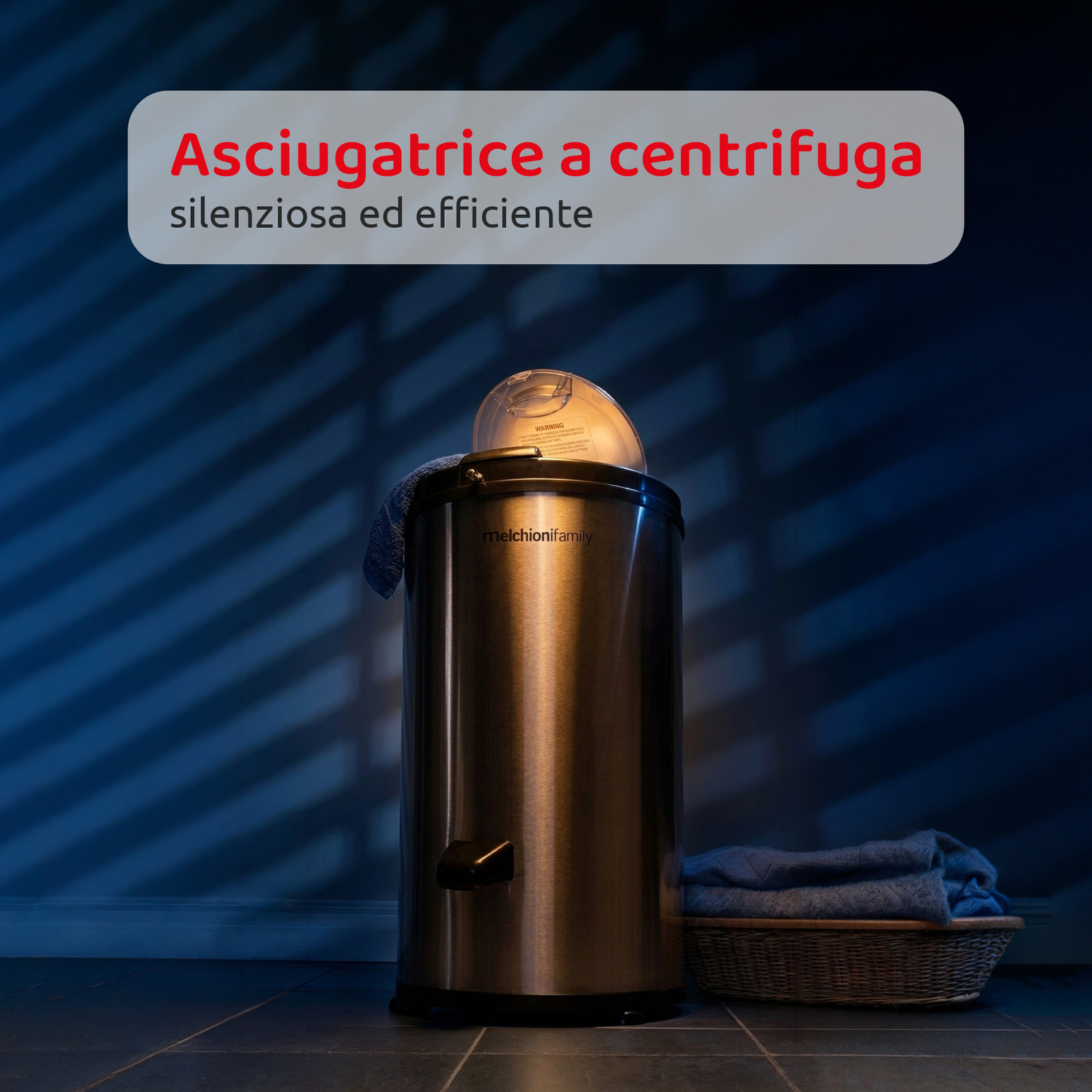 Una centrifuga asciugatrice in acciaio inox si trova in una stanza blu con un cesto di asciugamani e testo in italiano in alto.
