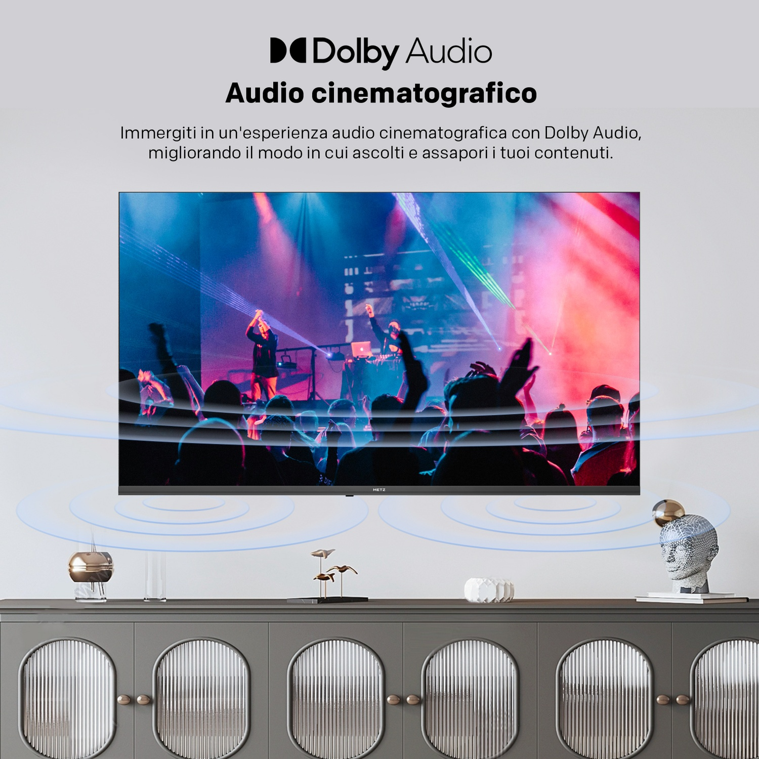 Una TV mostra un concerto con Dolby Audio, circondato da grafiche di onde acustiche su una credenza.