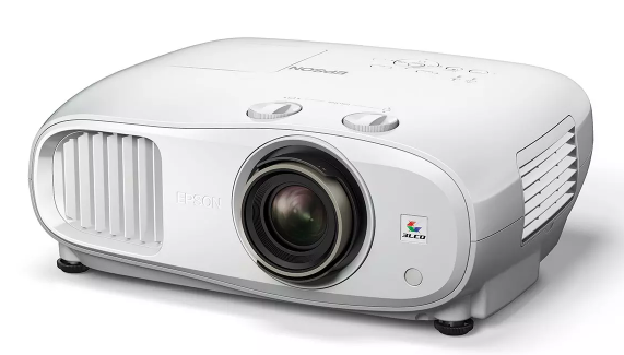 Biały projektor Epson z dużym obiektywem na środku, przyciskami sterującymi i kratkami wentylacyjnymi.