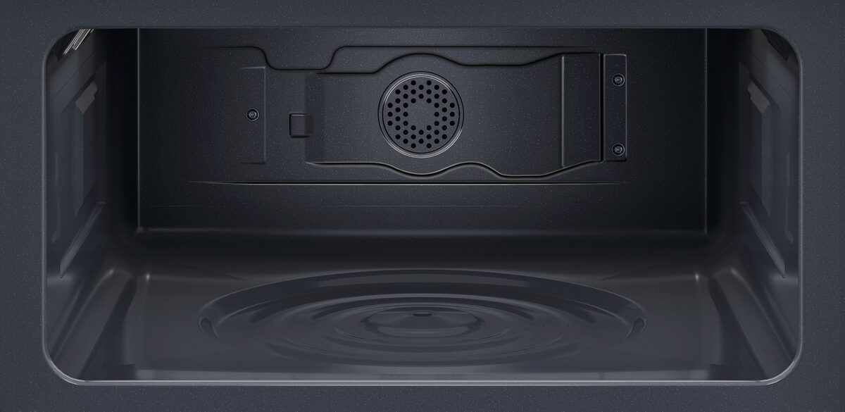 Interior de un horno oscuro con rejilla de ventilación circular y base lisa.
