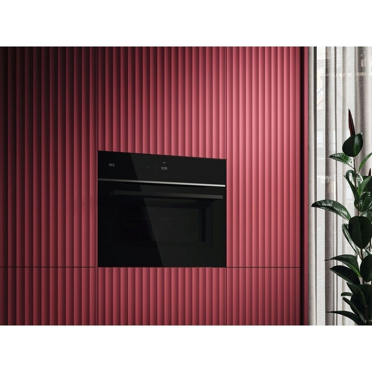 Un horno AEG negro está empotrado en una pared de paneles rojos acanalados, junto a una planta.