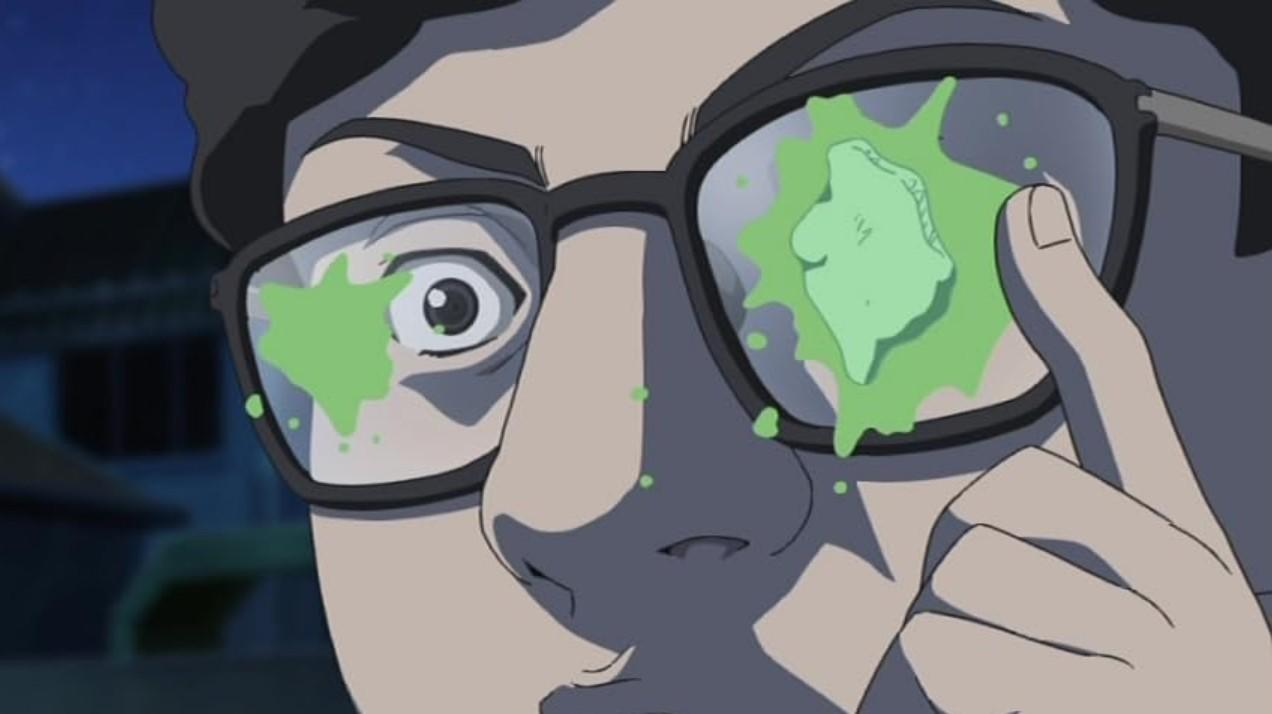 Ein Anime-Charakter mit Brille zeigt ein weit aufgerissenes Auge mit grünen Flecken auf den Gläsern.