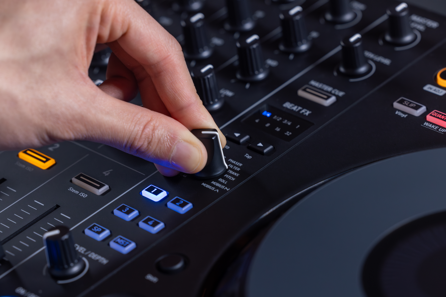 Una mano gira una perilla en un mezclador de DJ negro con botones azules.