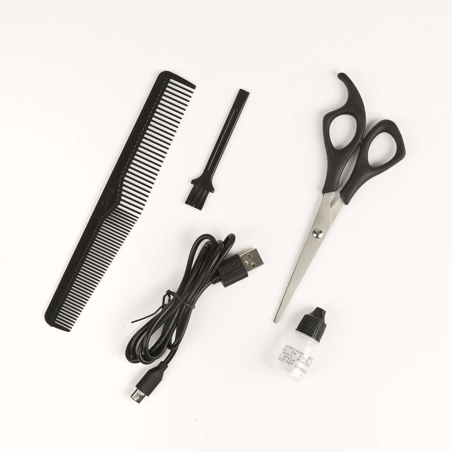 Un set con forbici, pettine, spazzola, cavo USB e olio su sfondo bianco.