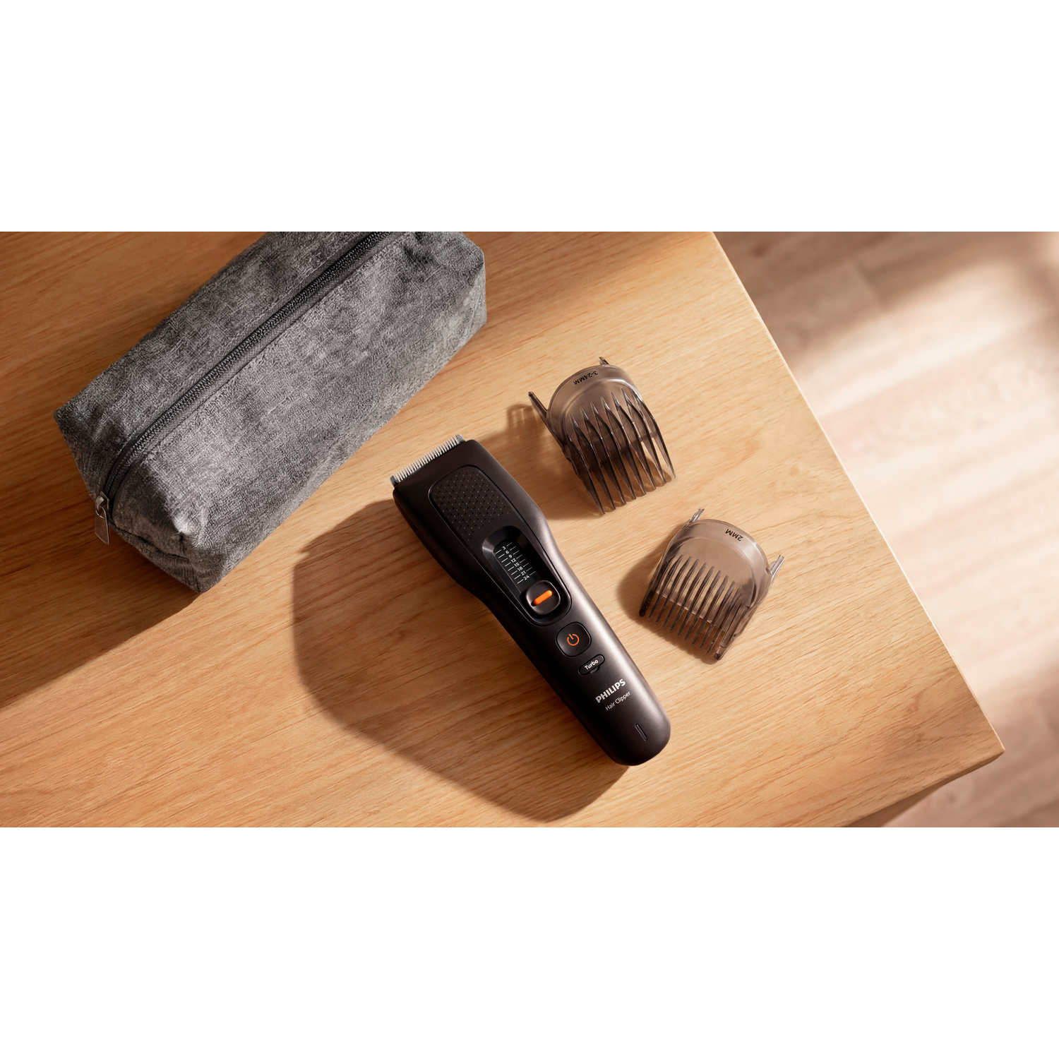 Un tagliacapelli Philips con due accessori e una custodia grigia su un tavolo di legno.