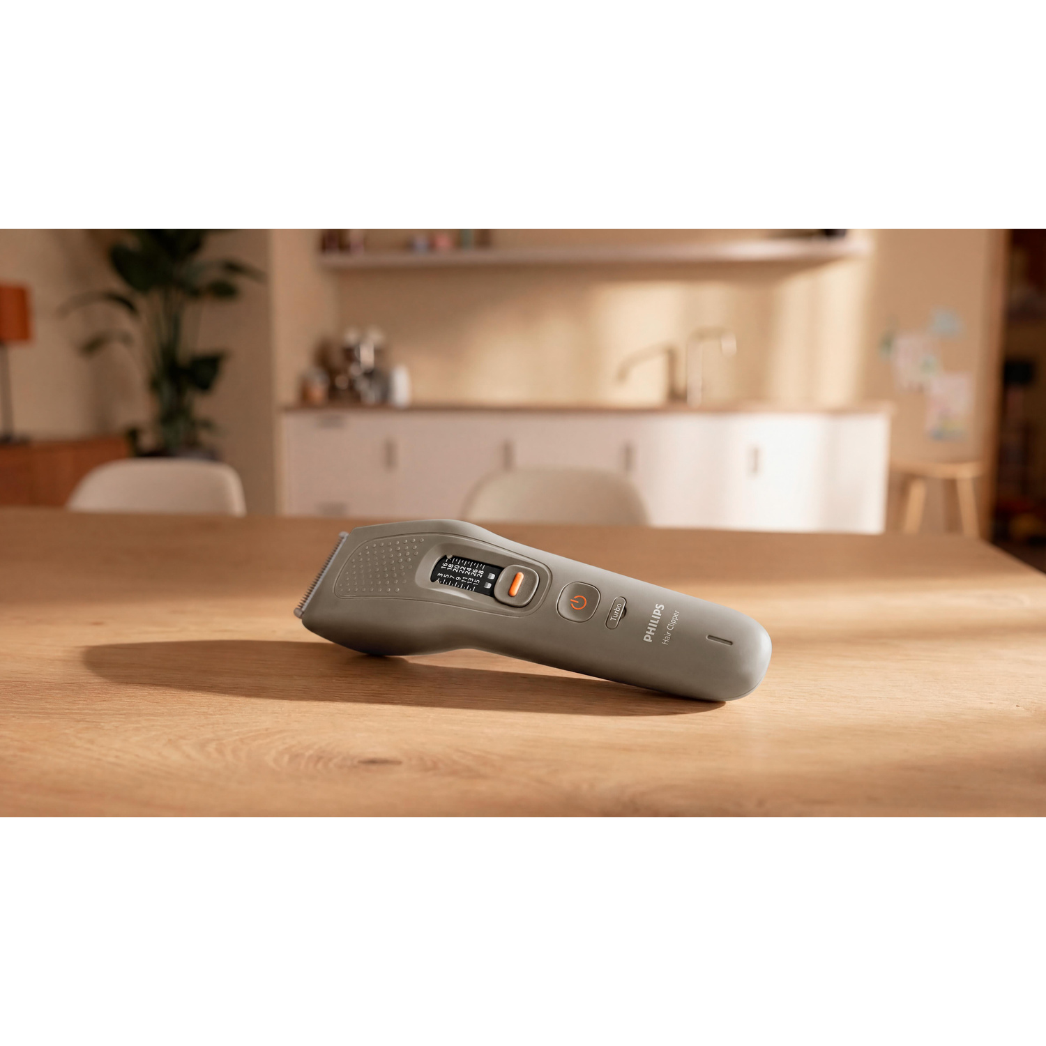 Un tagliacapelli Philips grigio è posato su un tavolo di legno davanti a uno sfondo sfocato.