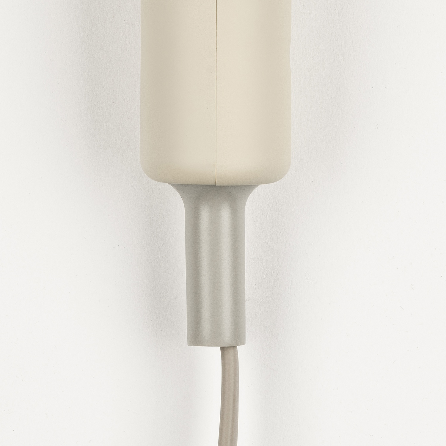 Un dispositivo elettronico beige con cavo grigio su sfondo bianco.