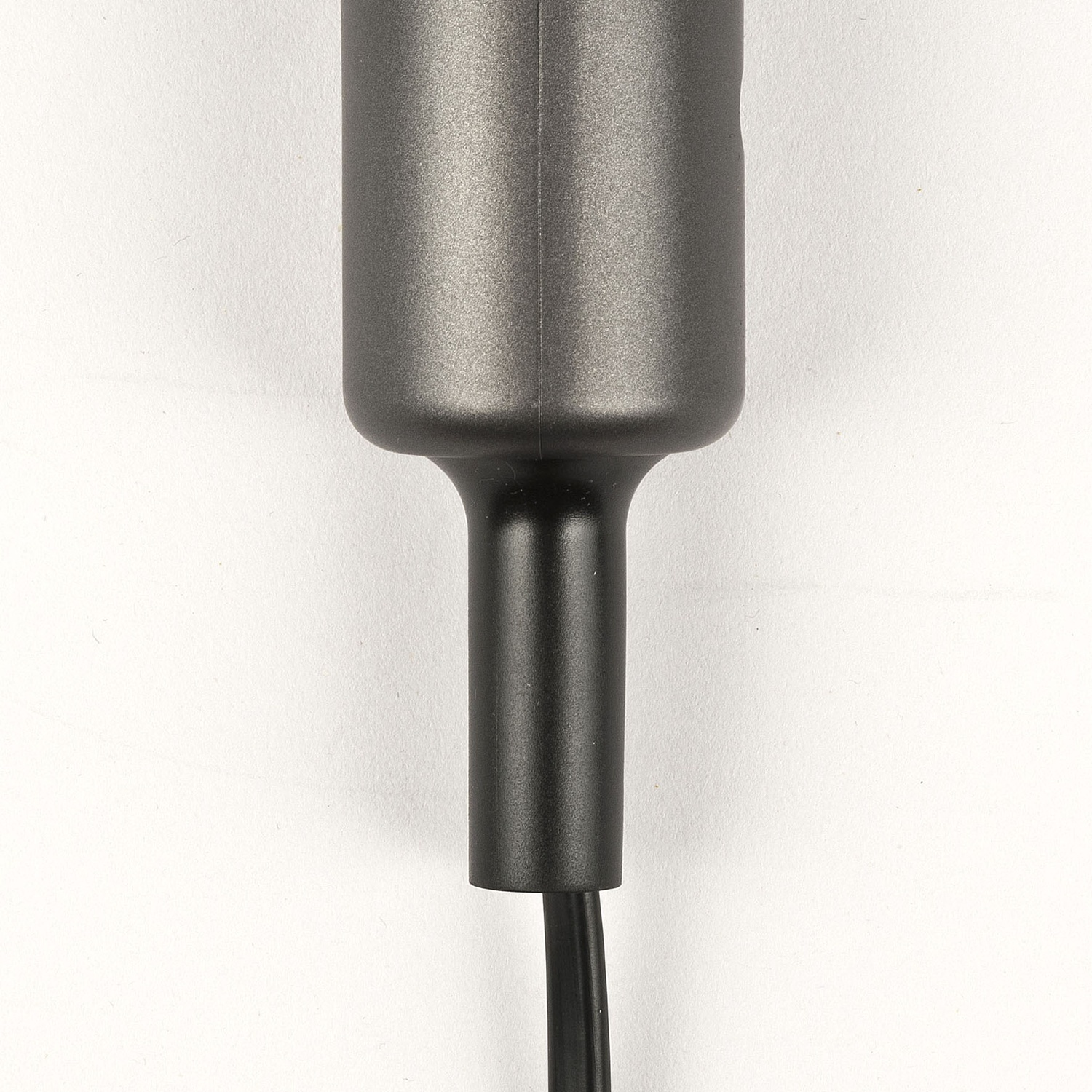Primo piano del manico di un dispositivo elettronico grigio scuro con un cavo di alimentazione nero.