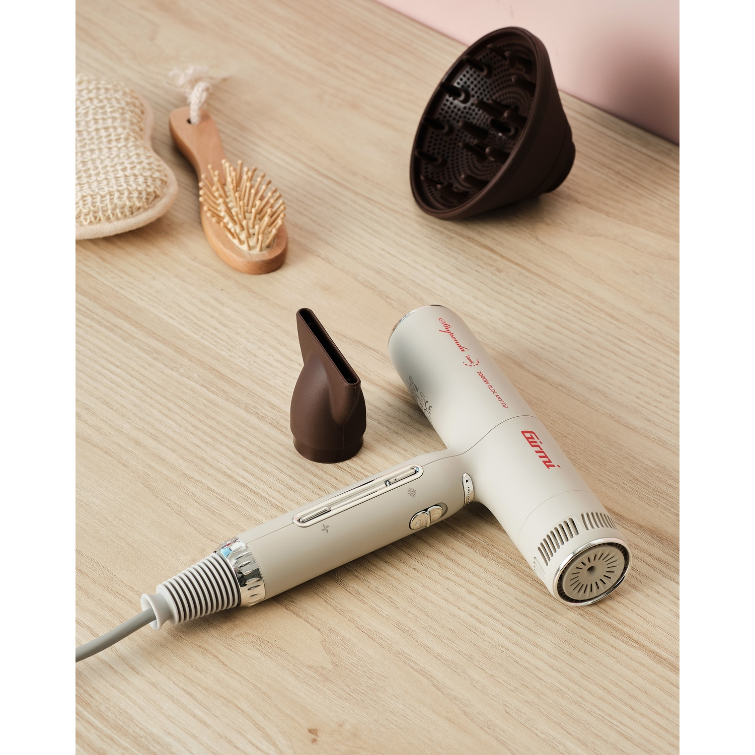 Un asciugacapelli beige con accessori e una spazzola su una superficie di legno.