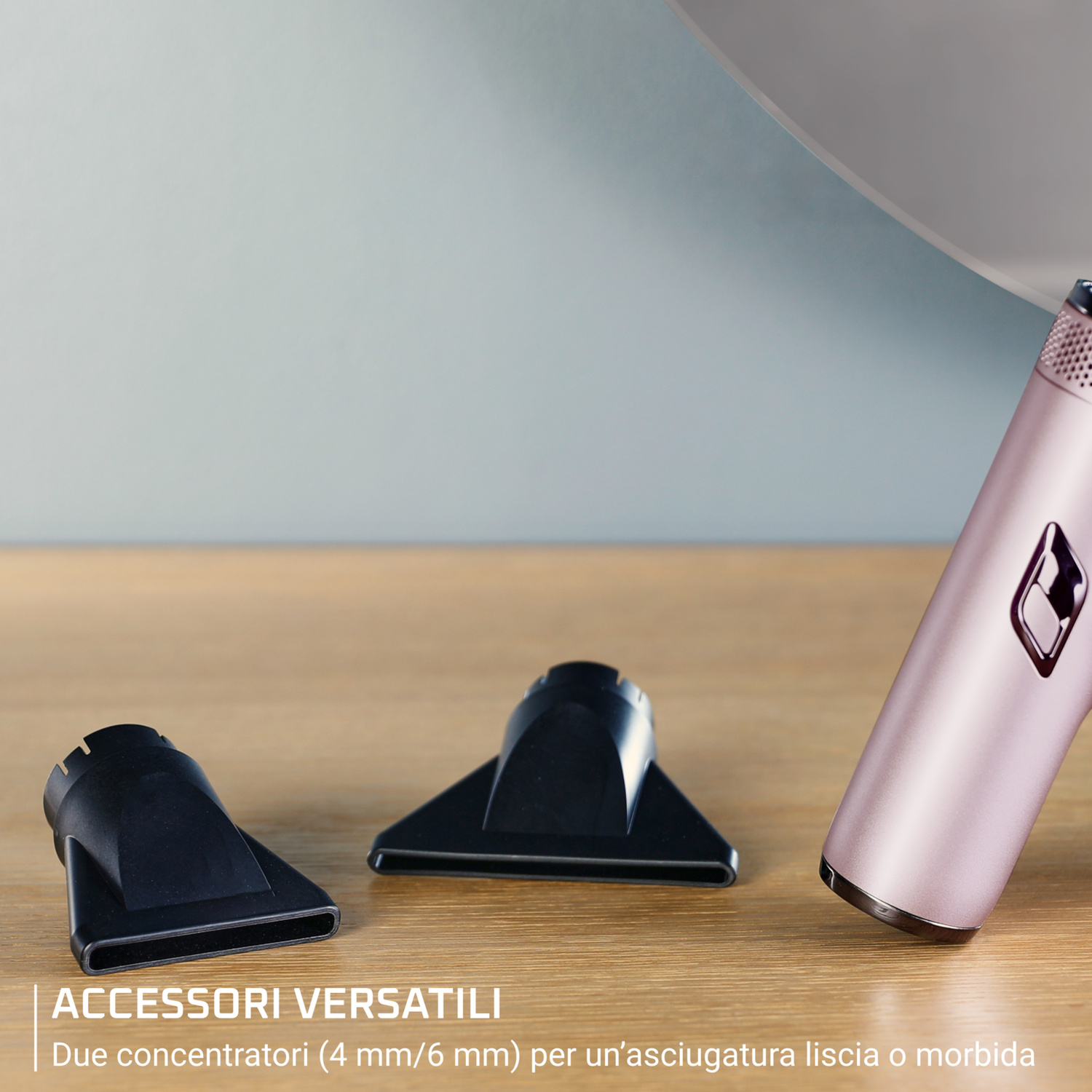 Asciugacapelli rosa con due beccucci concentratori neri su una superficie di legno.