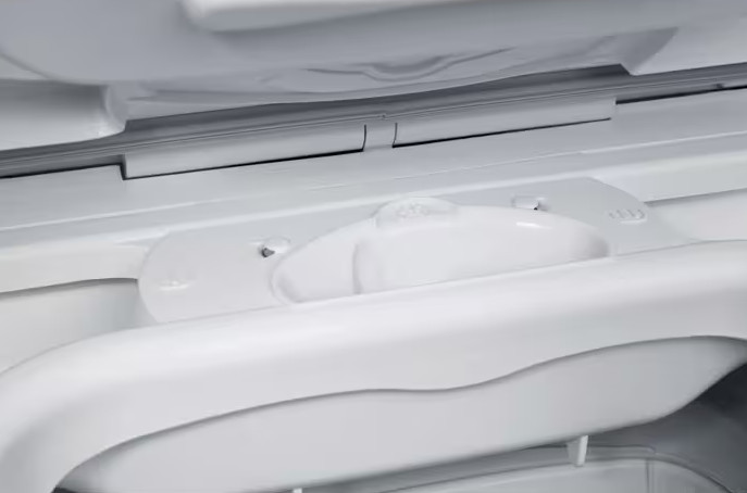 Zbliżenie na szufladę na detergent białej pralki, pokazujące czyste plastikowe powierzchnie.