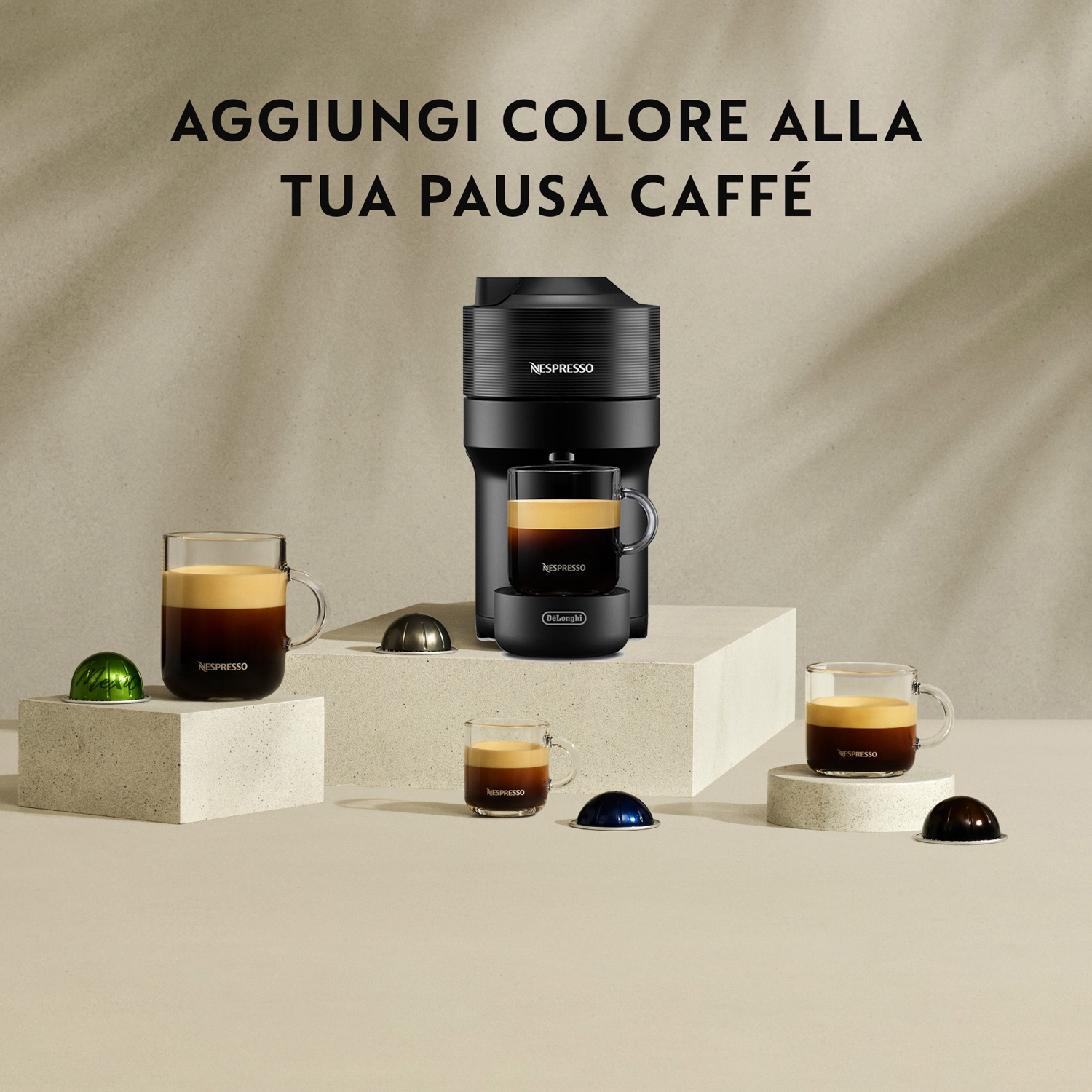 Macchina da caffè Nespresso nera con tazze e capsule colorate su piedistalli e scritta Aggiungi colore alla tua pausa caffè.