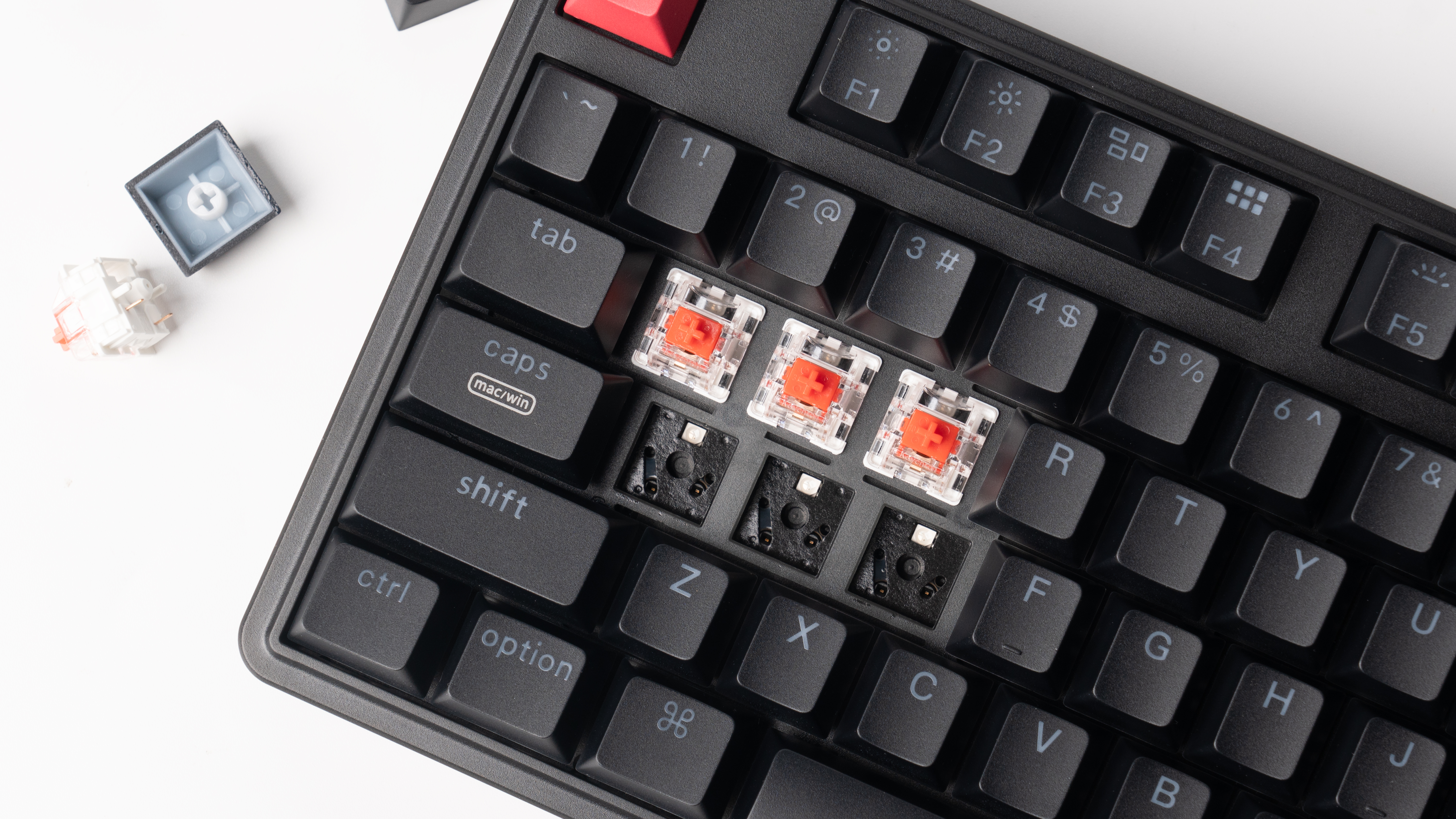 Schwarze Tastatur mit roten mechanischen Schaltern und entfernten Tastenkappen auf weißem Hintergrund.