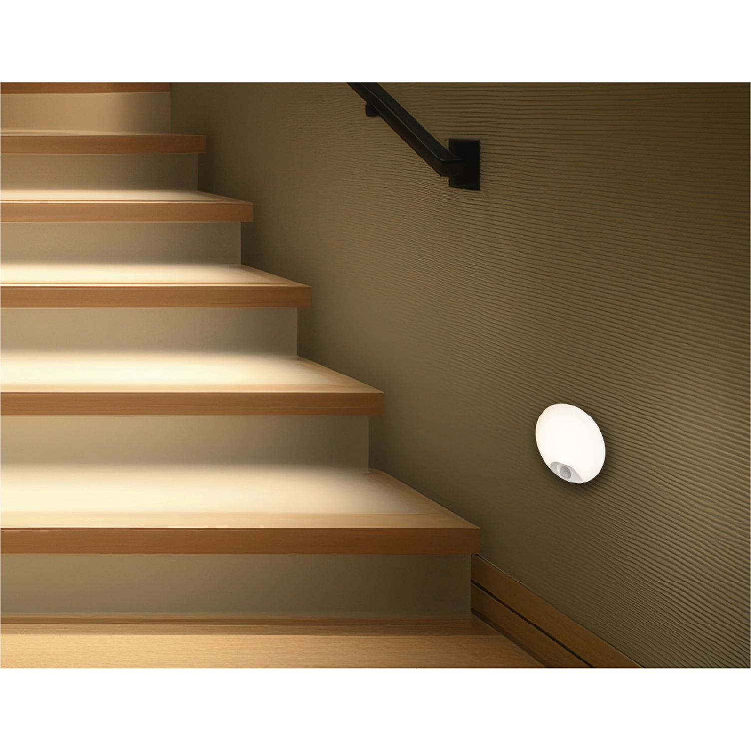 Een ronde wandlamp is gemonteerd op een gestructureerde muur naast verlichte houten trap.
