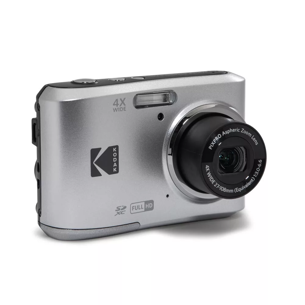 Ezüstszínű Kodak kompakt fényképezőgép fekete lencsével és vakuval fehér háttér előtt.