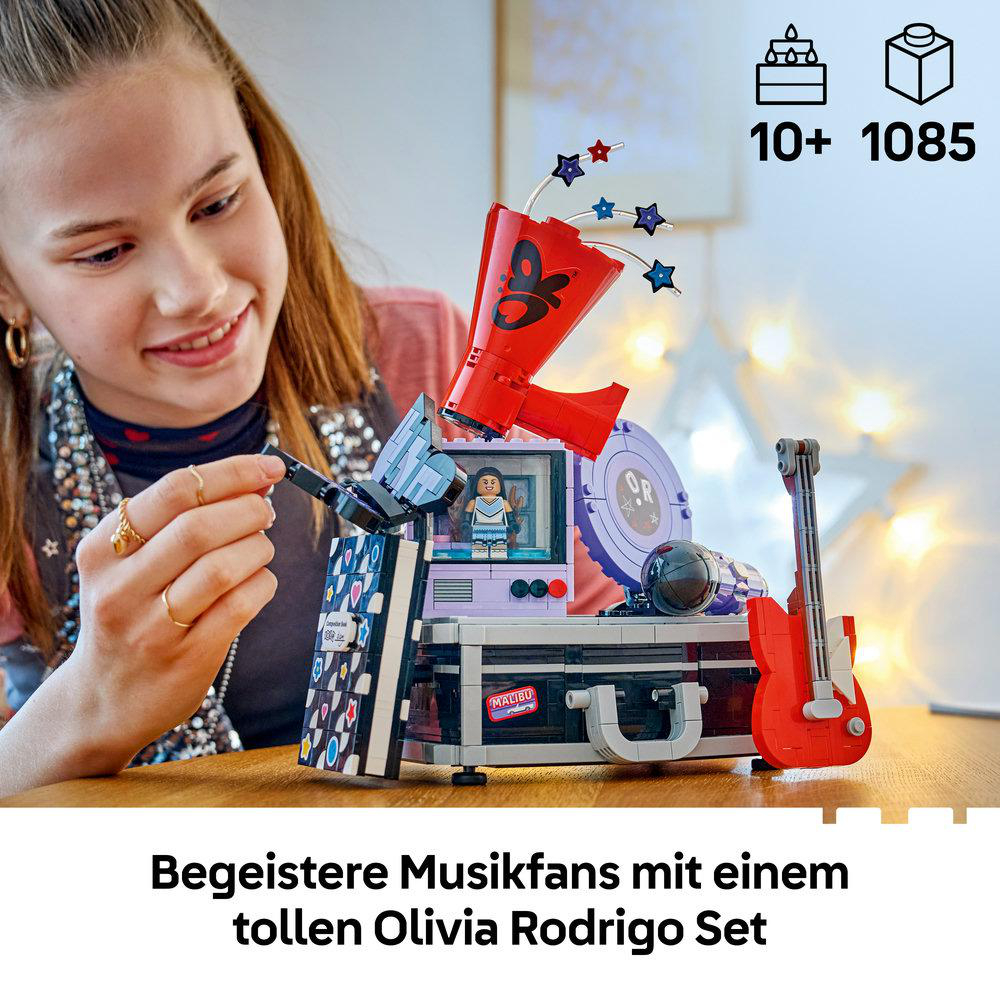 Ein Mädchen baut ein pinkes und schwarzes LEGO-Musikset mit einer roten Gitarre und Lautsprechern.